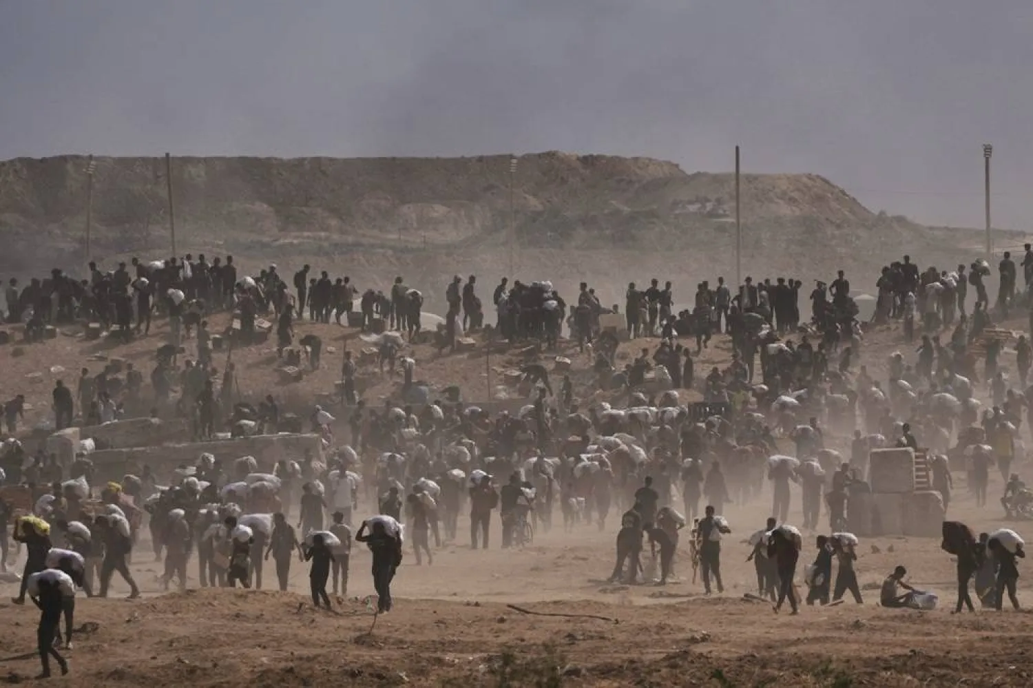  Palestinians carry humanitarian aid packages near a Gaza Humanitarian Foundation distribution center operated by the US-backed organization, in Netzarim, central Gaza Strip, Monday, Aug. 4, 2025. (AP) 