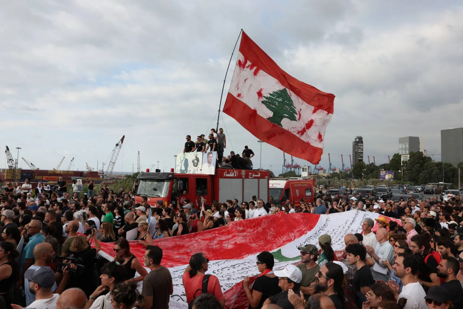 مشاركون في مسيرة الذكرة الخامسة لانفجار مرفأ بيروت يرفعون العلم اللبناني ويطالبون بتحقيق العدالة والوصول إلى الحقيقة (رويترز)