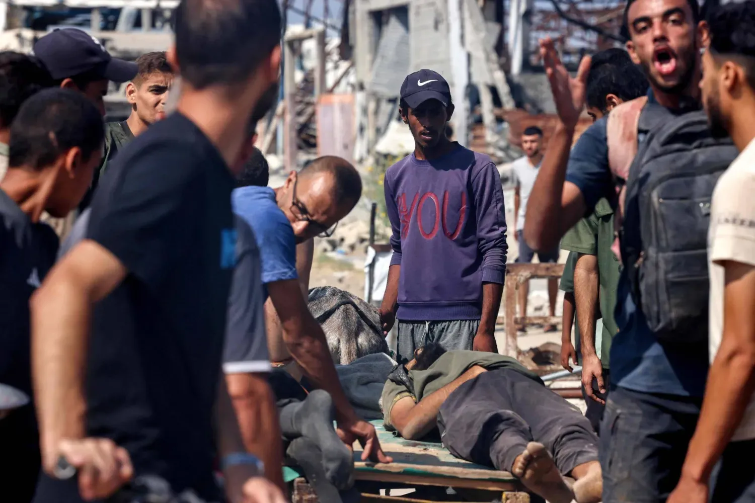 Filistinliler, Gazze Şeridi'nin merkezinde yardım bekleyenleri hedef alan İsrail saldırısında hayatını kaybedenlerin cenazelerinin etrafında toplanıyor (AFP)