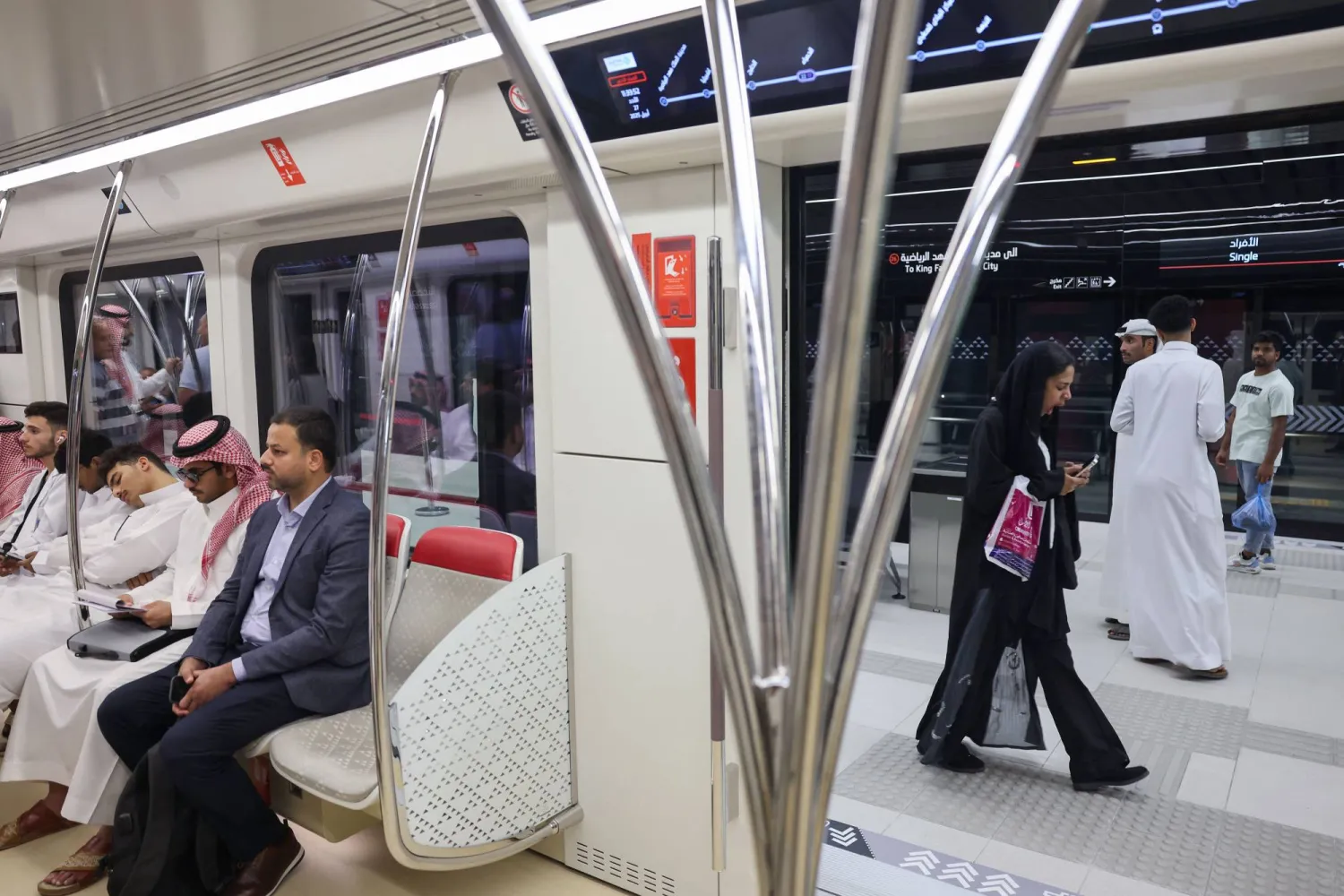 أشخاص يستقلون قطار الرياض متجهين إلى محطة جامعة الملك سعود (أ.ف.ب)