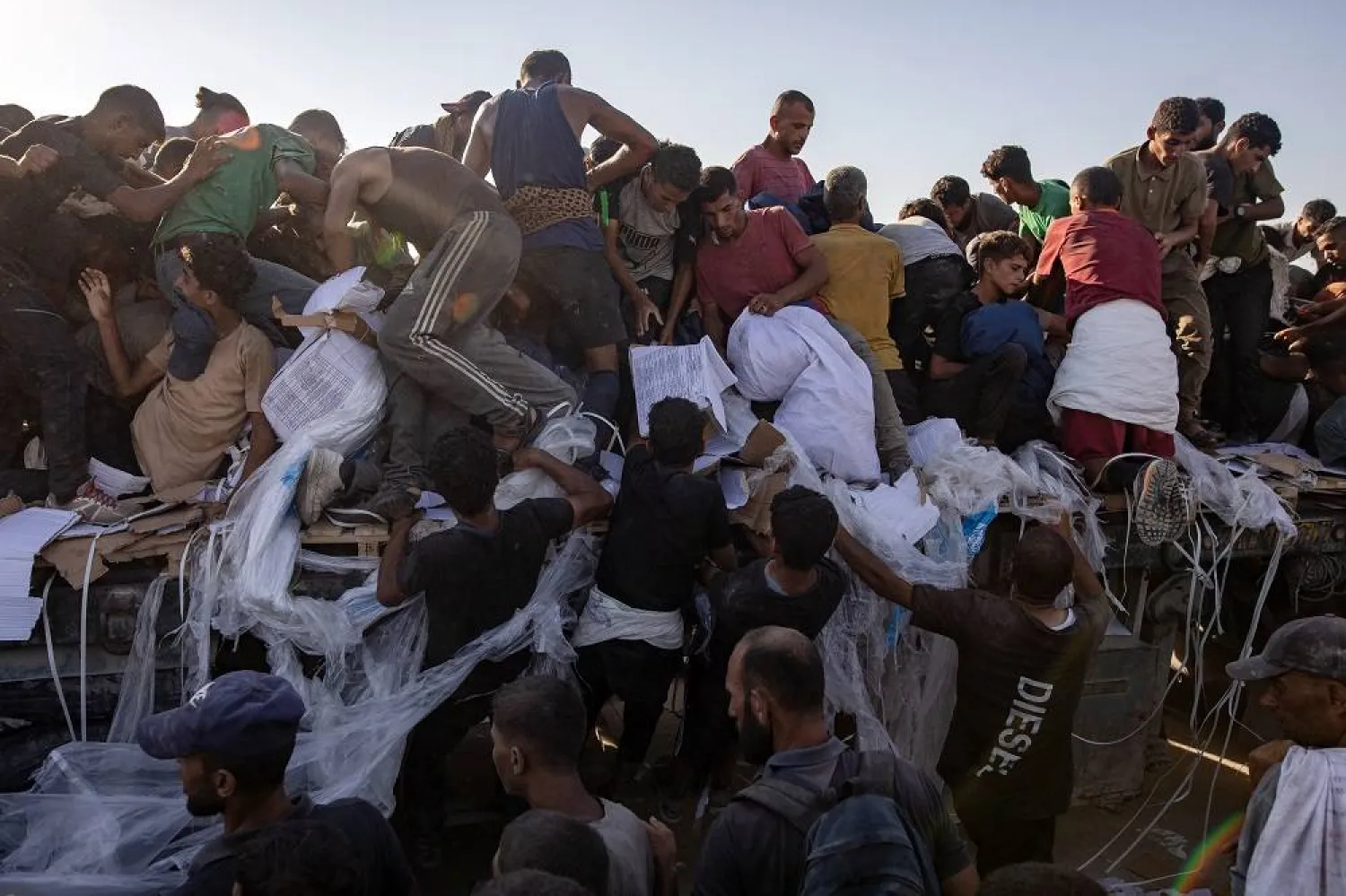 Internally displaced Palestinians climb aid trucks to get food near a food distribution point in the Morag corridor, south of Khan Younis, in the southern Gaza Strip, 04 August 2025. (EPA)