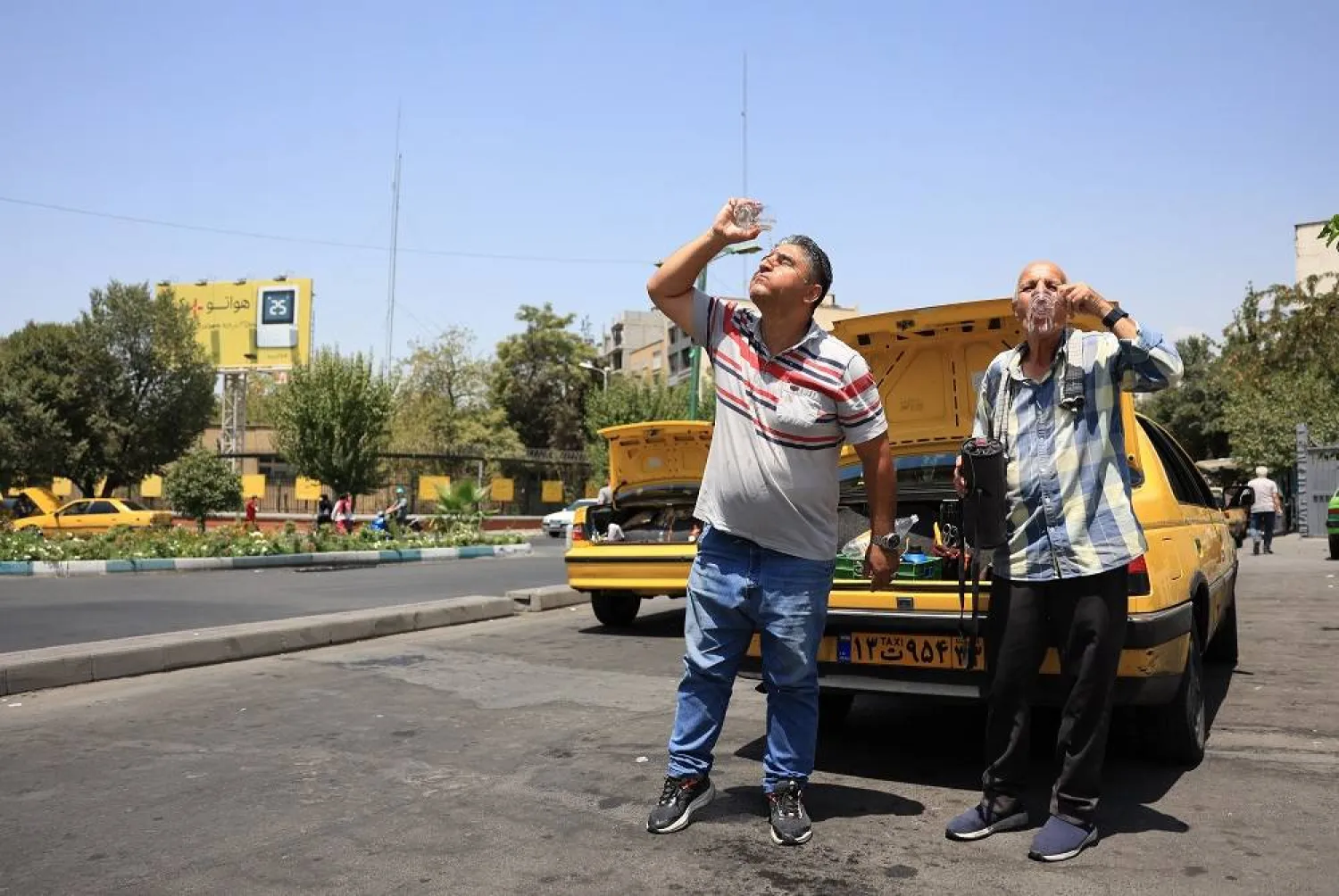 21 July 2025, Iran, Tehran: Two cab drivers cool off during a heatwave in the Iranian capital. (dpa)