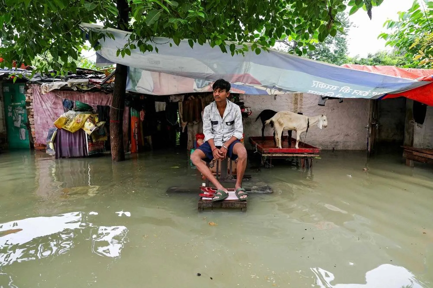 A man sits outside his house partially submerged in floodwaters after heavy monsoon rains induced a rise in water level of river Ganges in Varanasi on August 4, 2025. (AFP)