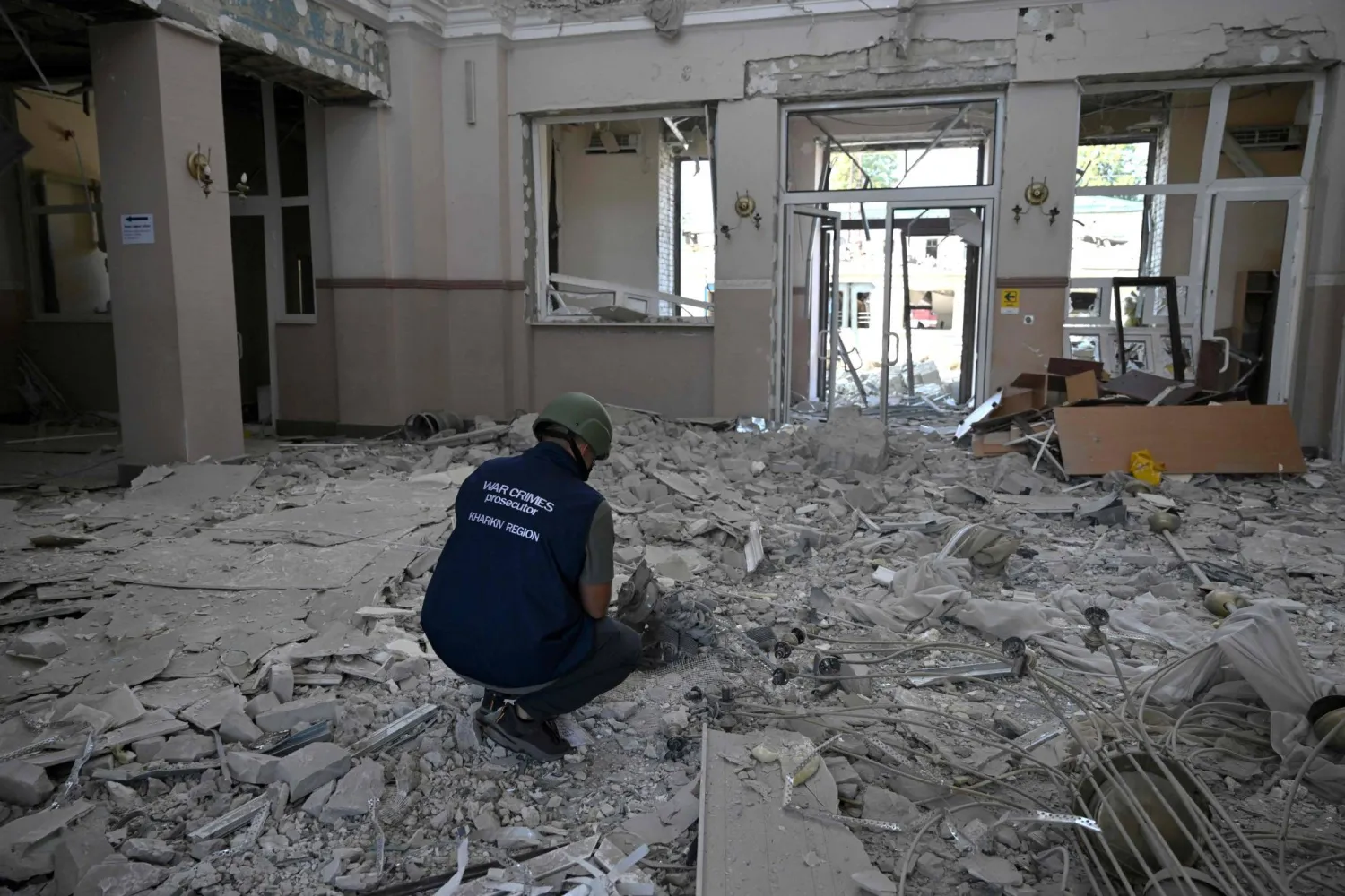 An investigator examines debris at a train station damaged following a drone strike in the town of Lozova, Kharkiv region on August 5, 2025, amid the Russian invasion of Ukraine. (Photo by Genya SAVILOV / AFP)

