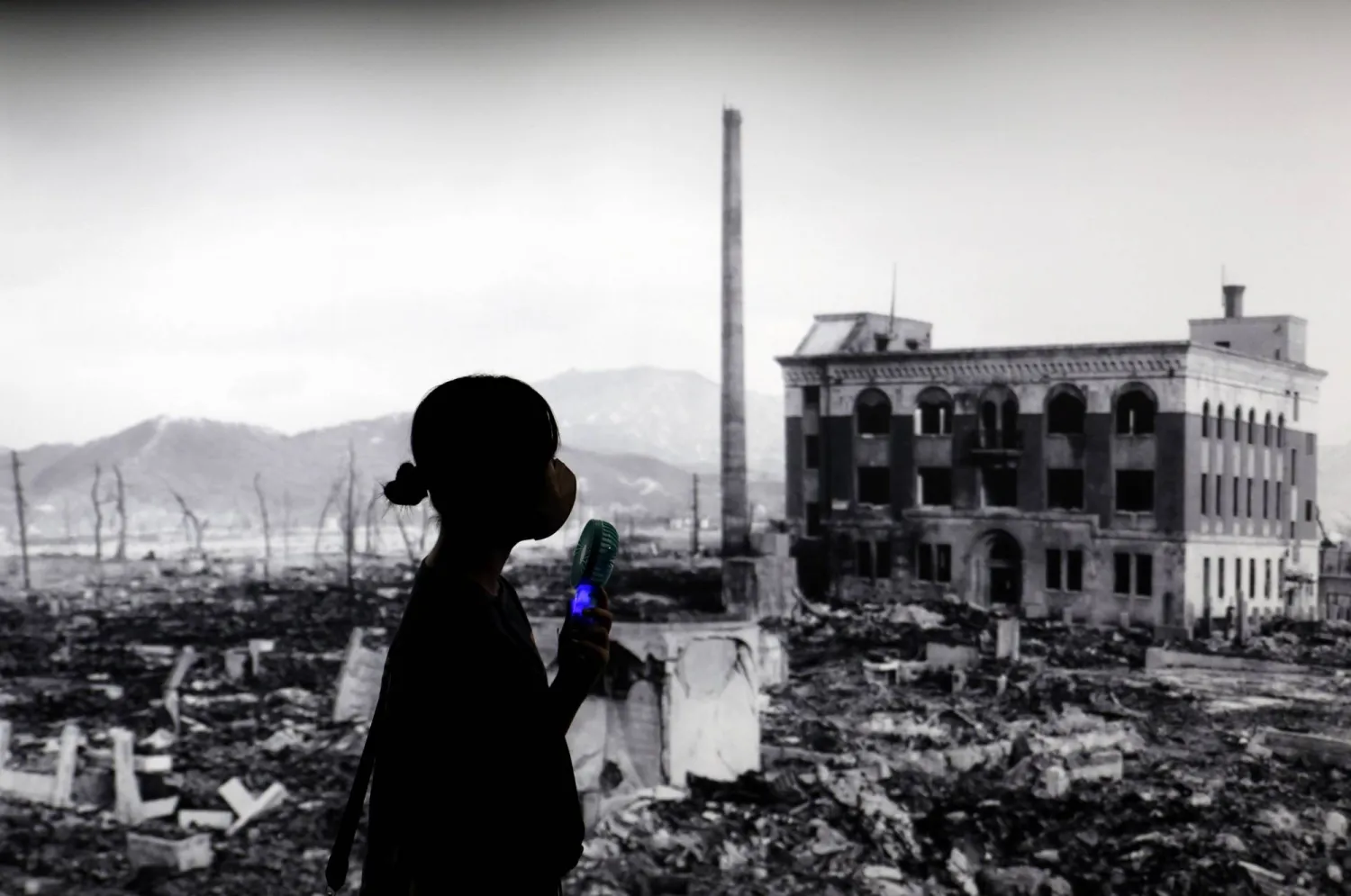 ​زائرة تمر أمام صورة ضخمة لهيروشيما المدمرة بسبب أول قصف نووي في العالم بالمتحف التذكاري للسلام بغرب اليابان (إ.ب.أ)