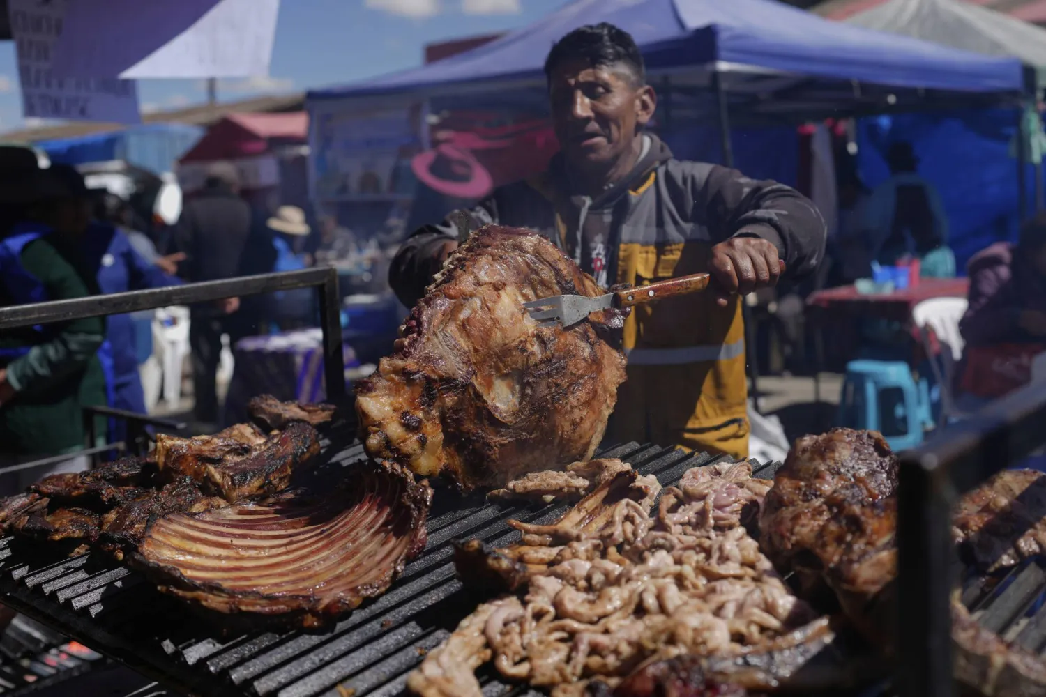 بائع يشوي اللحم خلال أحد المعارض في بوليفيا (أ.ب)