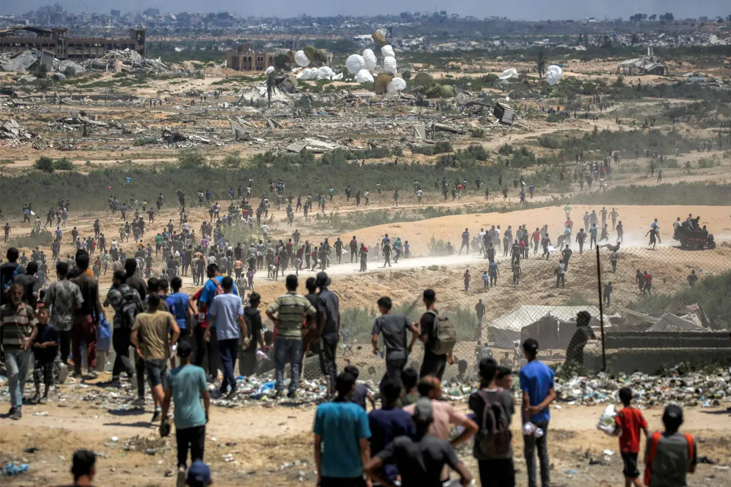 Filistinliler, Gazze Şeridi'nin merkezindeki Nuseyrat üzerinde bir askeri uçaktan paraşütle bırakılan insani yardımları almaya gidiyor (AFP)