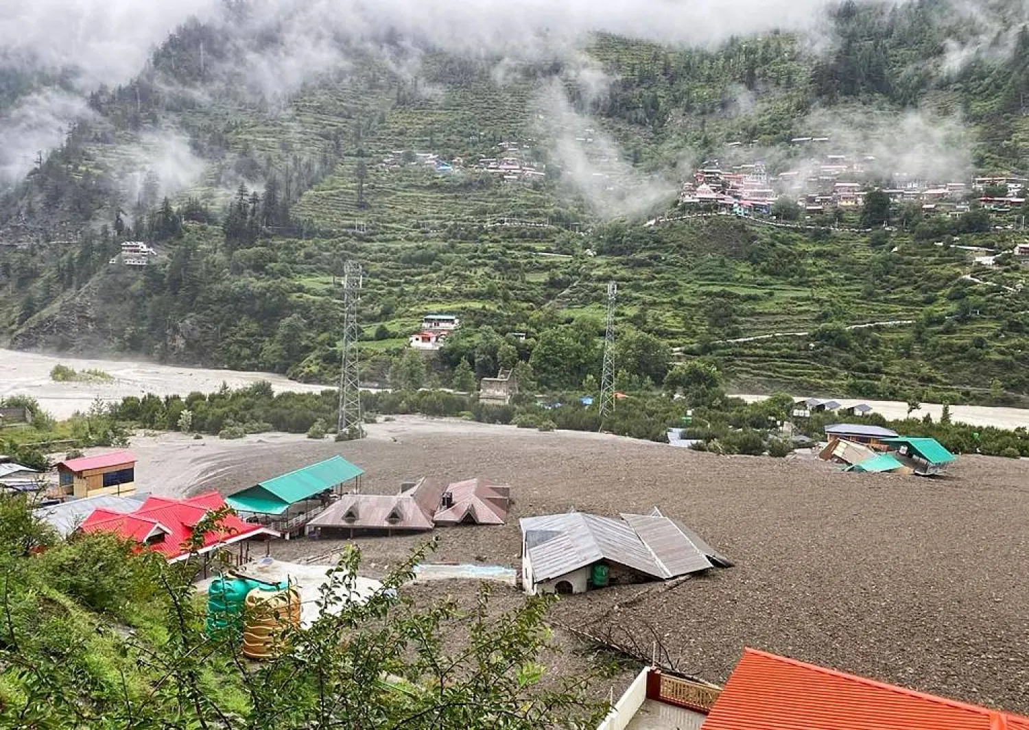 This handout photograph taken on August 5, 2025 and released by the Indian Army shows residential buildings partially submerged in sludge after a cloudburst caused a massive mudslide in India's Uttarakhand state. (Army / AFP / Handout) 