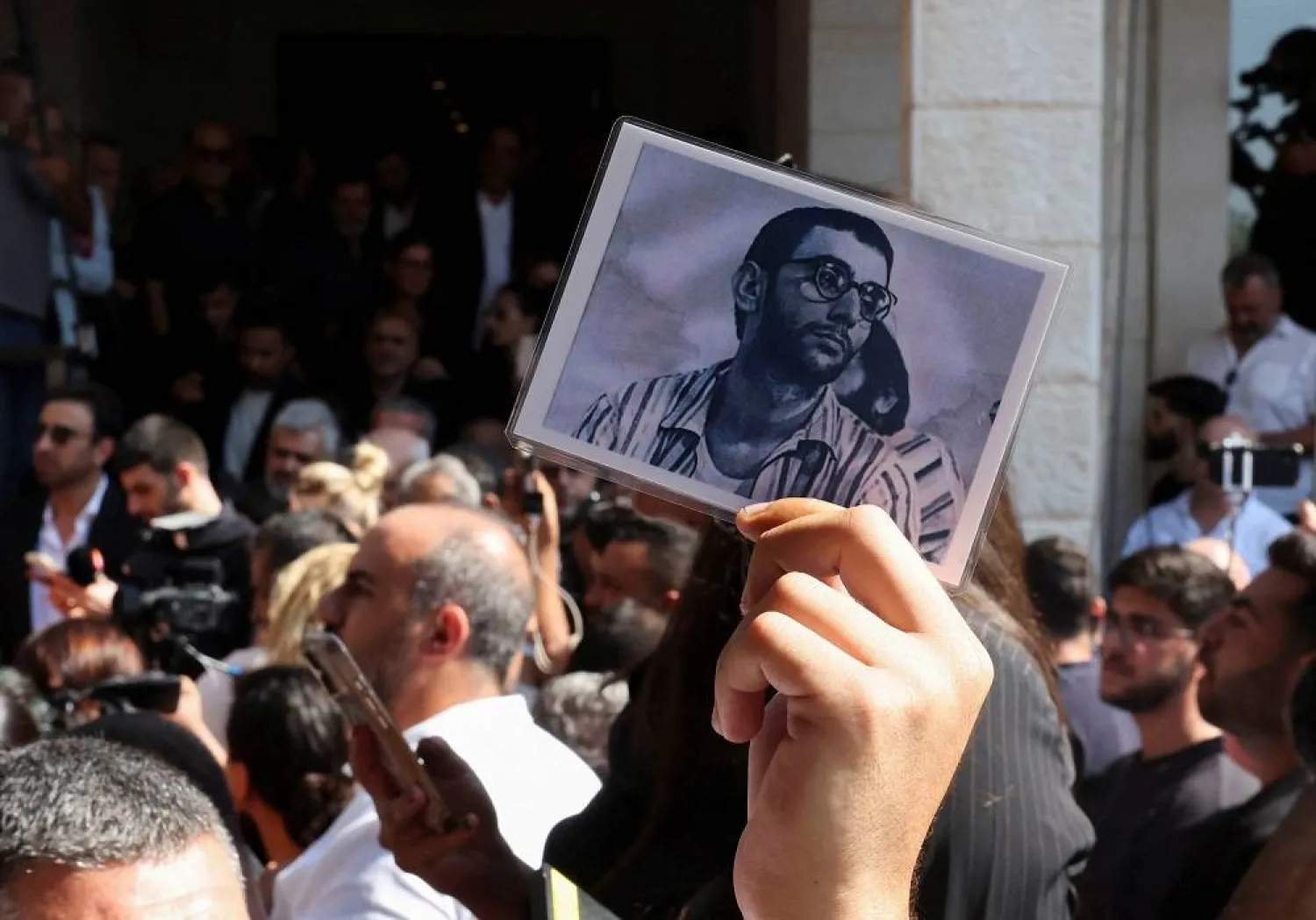 A mourner holds a picture of Ziad Rahbani, the Lebanese composer and musician who passed away on Saturday, during his funeral in Bikfaya, Lebanon July 28, 2025. (Reuters)