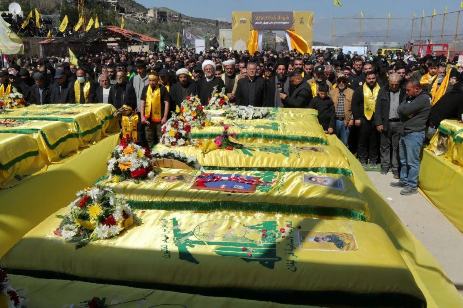 Mourners surround the flag-draped coffins of Hezbollah fighters, during their funeral along with civilians killed in the recent war with Israel, in the southern Lebanese border village of Kfar Kila on March 9, 2025. (AFP)