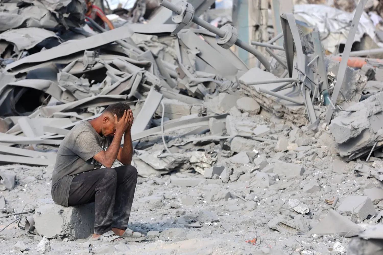Gazze şehrinin kuzeyindeki Birleşmiş Milletler Yakın Doğu'daki Filistinli Mültecilere Yardım ve Bayındırlık Ajansı (UNRWA) merkezine düzenlenen hava saldırısının yol açtığı yıkımın ortasında oturan bir Filistinli (AFP)