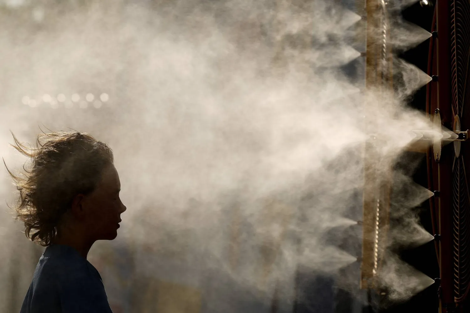 FILE PHOTO - Michael Mullenax, 10, from Lee's Summit, Mo., cools off in a mister at Kauffman Stadium before a baseball game between the Kansas City Royals and the Miami Marlins, June 24, 2024, in Kansas City, Mo. (AP Photo/Charlie Riedel, File)