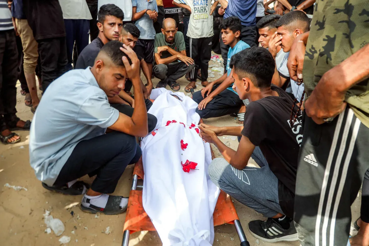 Han Yunus'un el-Mevasi bölgesinde yerinden edilmiş kişiler için kurulan kampa İsrail tarafından gece boyunca düzenlenen bombardıman sonucu hayatını kaybeden yakınlarının cenazesi başında toplanan Filistinliler (AFP)