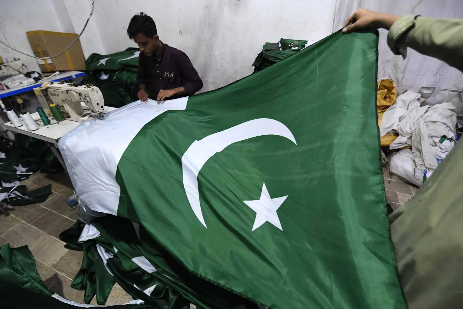 حِرفيٌ يخيط الأعلام الوطنية بمصنع قبل احتفالات «يوم الاستقلال» الباكستاني... في كراتشي بباكستان يوم 6 أغسطس 2025... ويُحتفل بهذا اليوم سنوياً في 14 أغسطس لإحياء ذكرى نهاية الحكم الاستعماري البريطاني عام 1947 (إ.ب.أ)