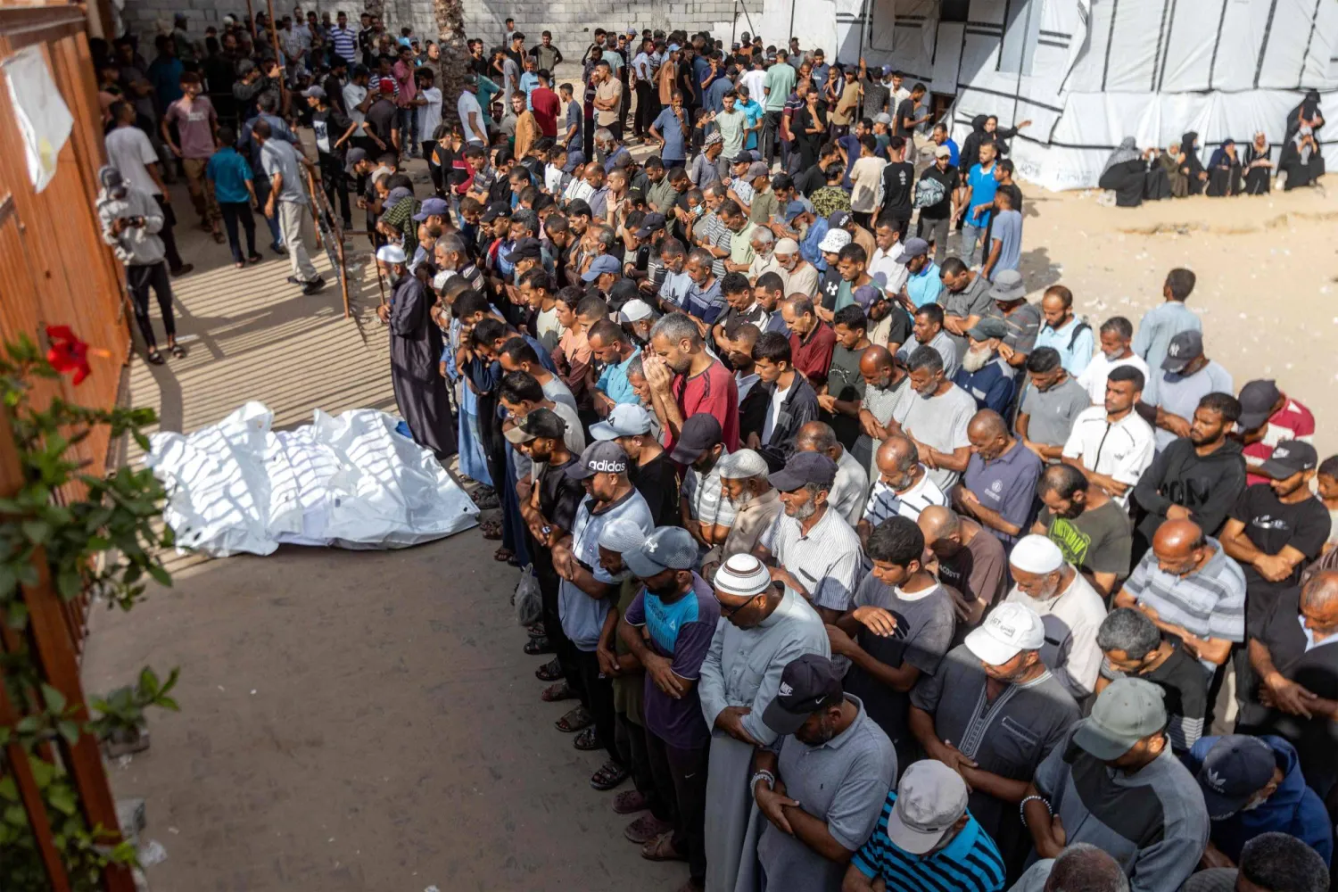 EDITORS NOTE: Graphic content / Mourners pray by the body of one of the victims killed during overnight Israeli bombardment on a camp sheltering displaced people in the Mawasi area of Khan Yunis, during the funeral at Nasser Medical Complex in Khan Yunis in the southern Gaza Strip on August 5, 2025. (Photo by AFP)
