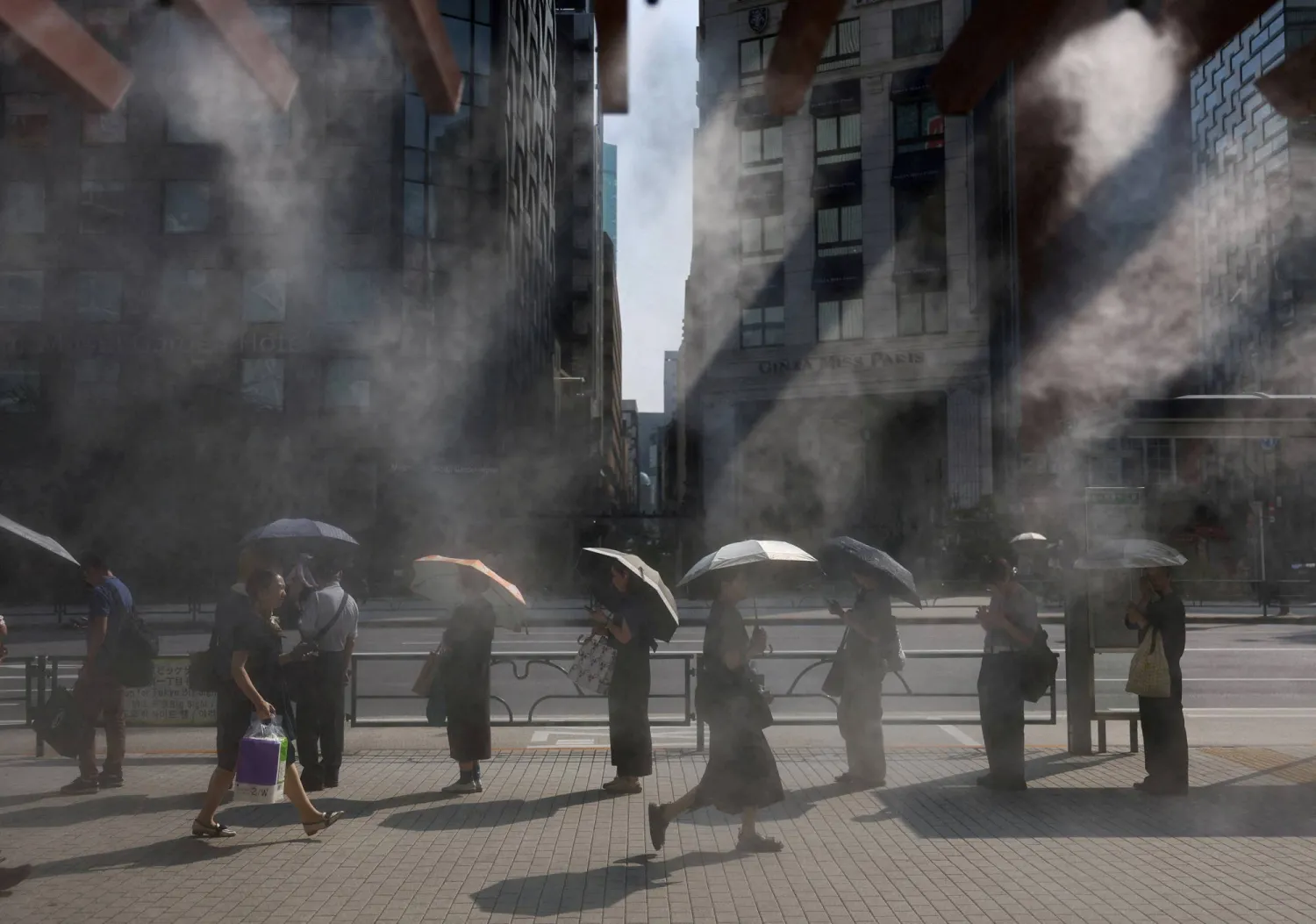 يابانيون ينتظرون حافلة بأحد شوارع العاصمة طوكيو وسط أجواء شديدة الحرارة (رويترز)
