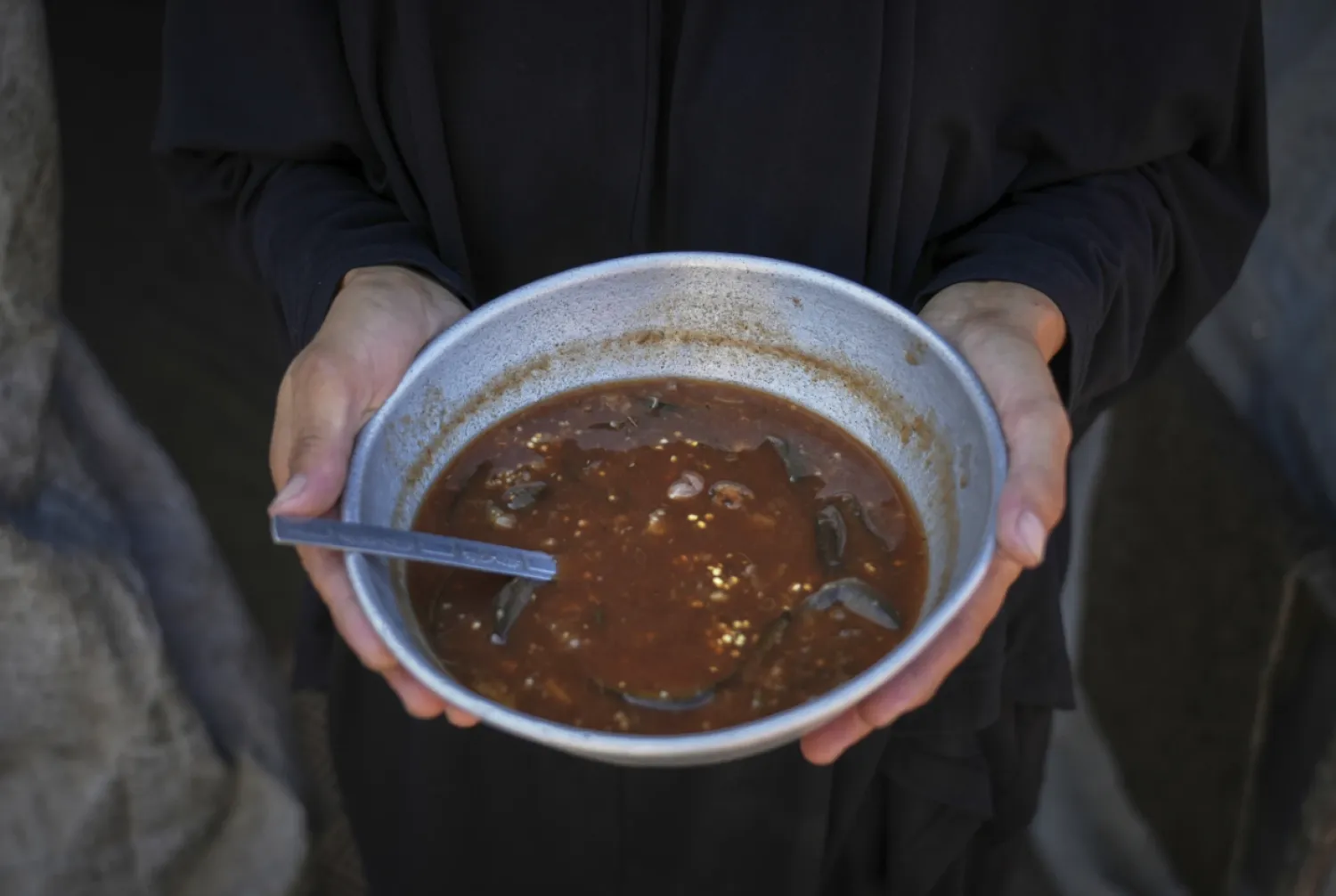 Palestinian woman Sally Muzhed, 38, displaced from Deir al-Balah, poses for a picture holding a plate with eggplant, her only food for the day, amid severe food shortages in the Gaza Strip, in Deir al-Balah, Monday, Aug. 4, 2025. (AP Photo/Abdel Kareem Hana)
