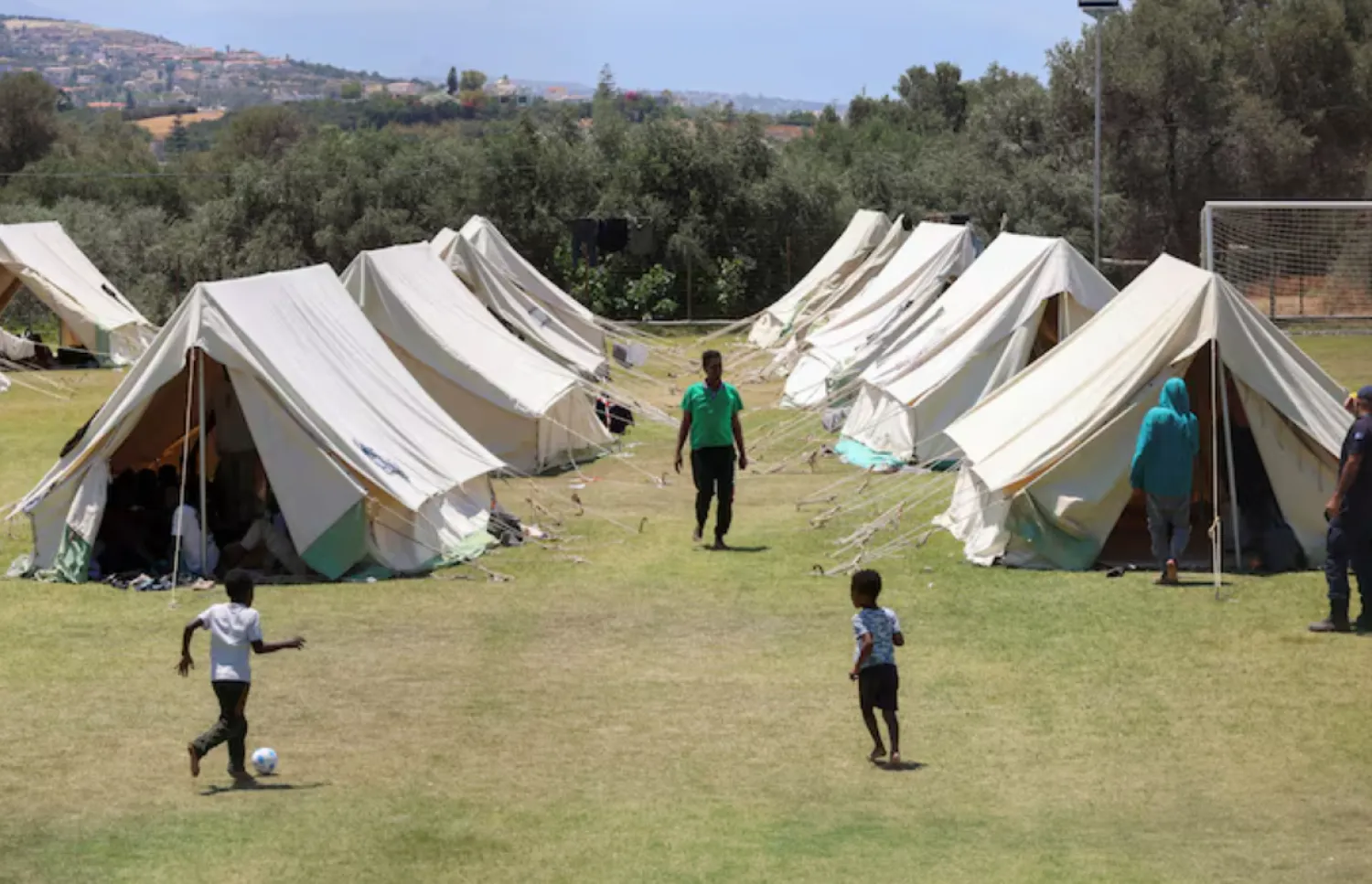 Children play near tents as recently arrived migrants shelter at a temporary camp set up on a soccer pitch in the region of Rethymno on Crete island, Greece, June 24, 2025. REUTERS/Stefanos Rapanis/File Photo 