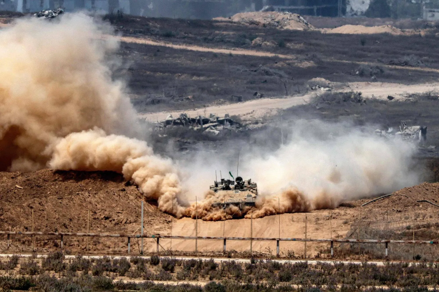 An Israeli army infantry-fighting vehicle (IFV) leaves a cloud of dust as it moves at a position along Israel's southern border with the Gaza Strip on August 5, 2025. (Photo by Jack GUEZ / AFP)