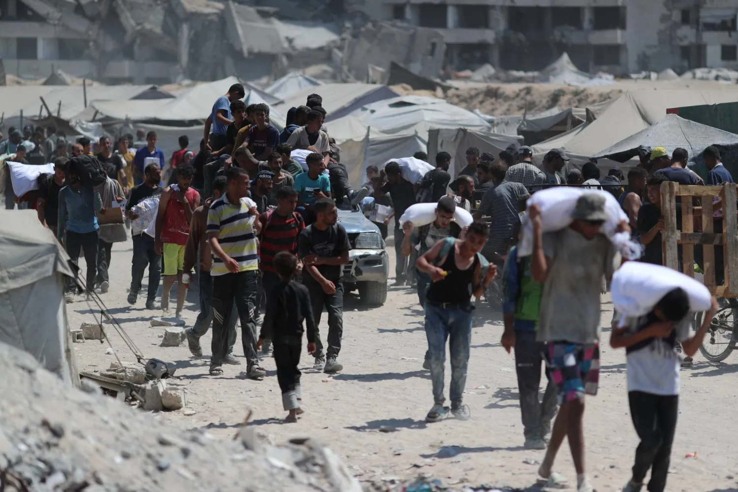 صورة ملتقطة في 7 أغسطس 2025 في مدينة غزة تظهر فلسطينيين يحملون إمدادات مساعدة تلقوها من «مؤسسة غزة الإنسانية» المدعومة من الولايات المتحدة (د.ب.أ)
