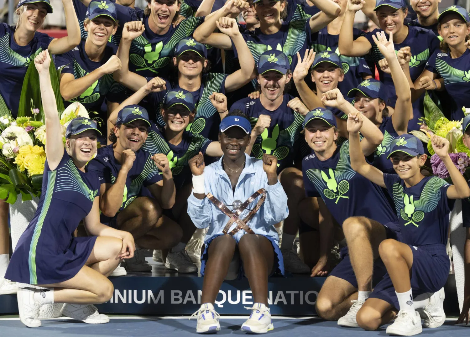 Victoria Mboko, center front, of Canada, poses with the ball crew following her win over Naomi Osaka, of Japan, in final action at the National Bank Open women's tennis tournament in Montreal, Thursday, Aug. 7, 2025. (Christinne Muschi/The Canadian Press via AP)