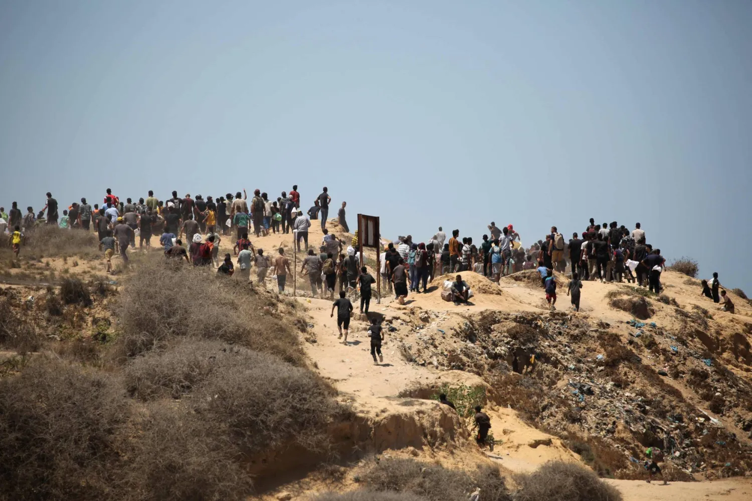 Palestinians rush to the site where parachuted aid packages are landing in the Nuseirat area in the central Gaza Strip during an airdrop above the Israel-besieged Palestinian territory on August 6, 2025. (Photo by Eyad BABA / AFP)