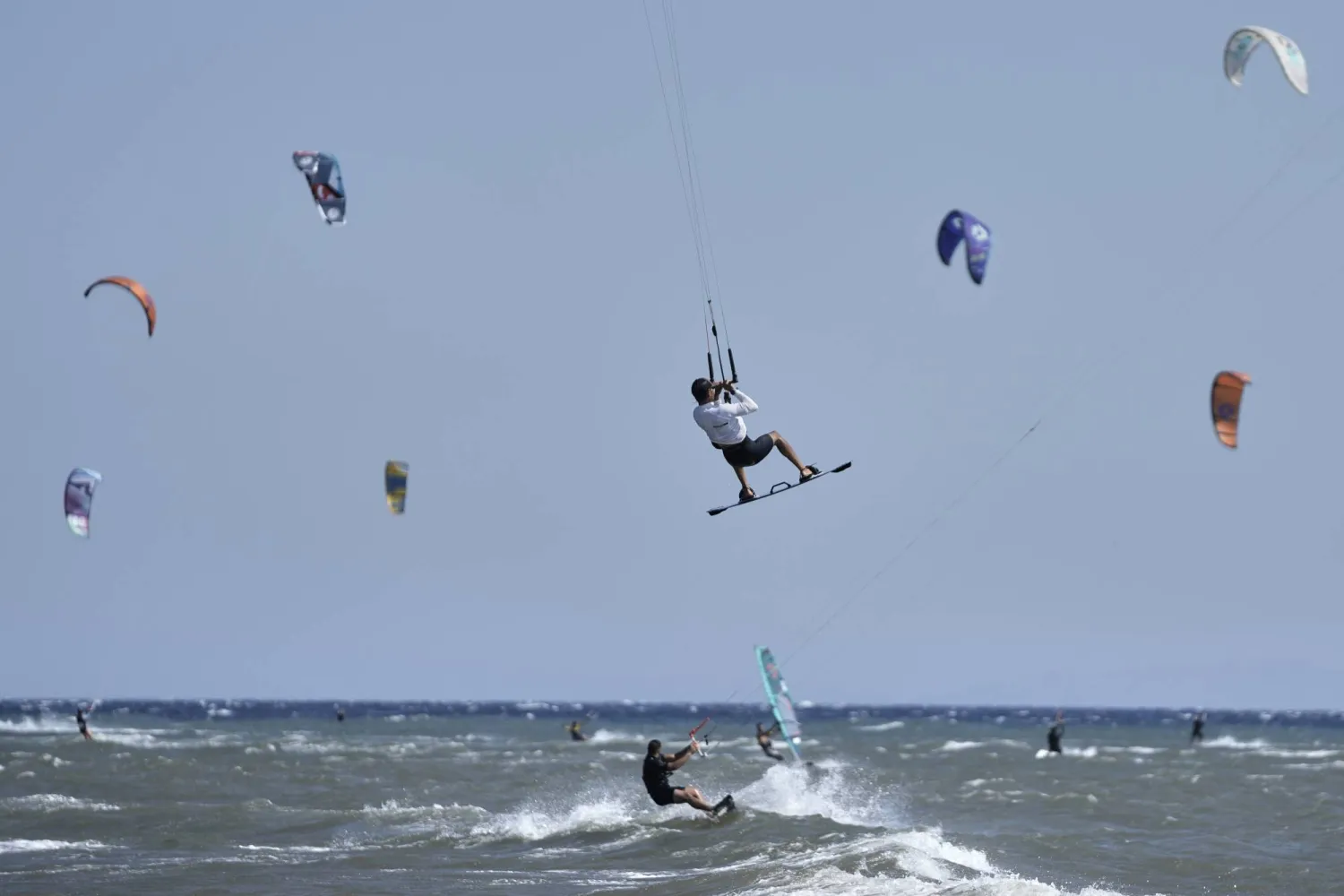 A kiteboarder performs a jump during a windy day in Agios Nikolaos Artemida, east of Athens, Greece, Thursday, Aug. 7, 2025. (AP Photo/Thanassis Stavrakis)