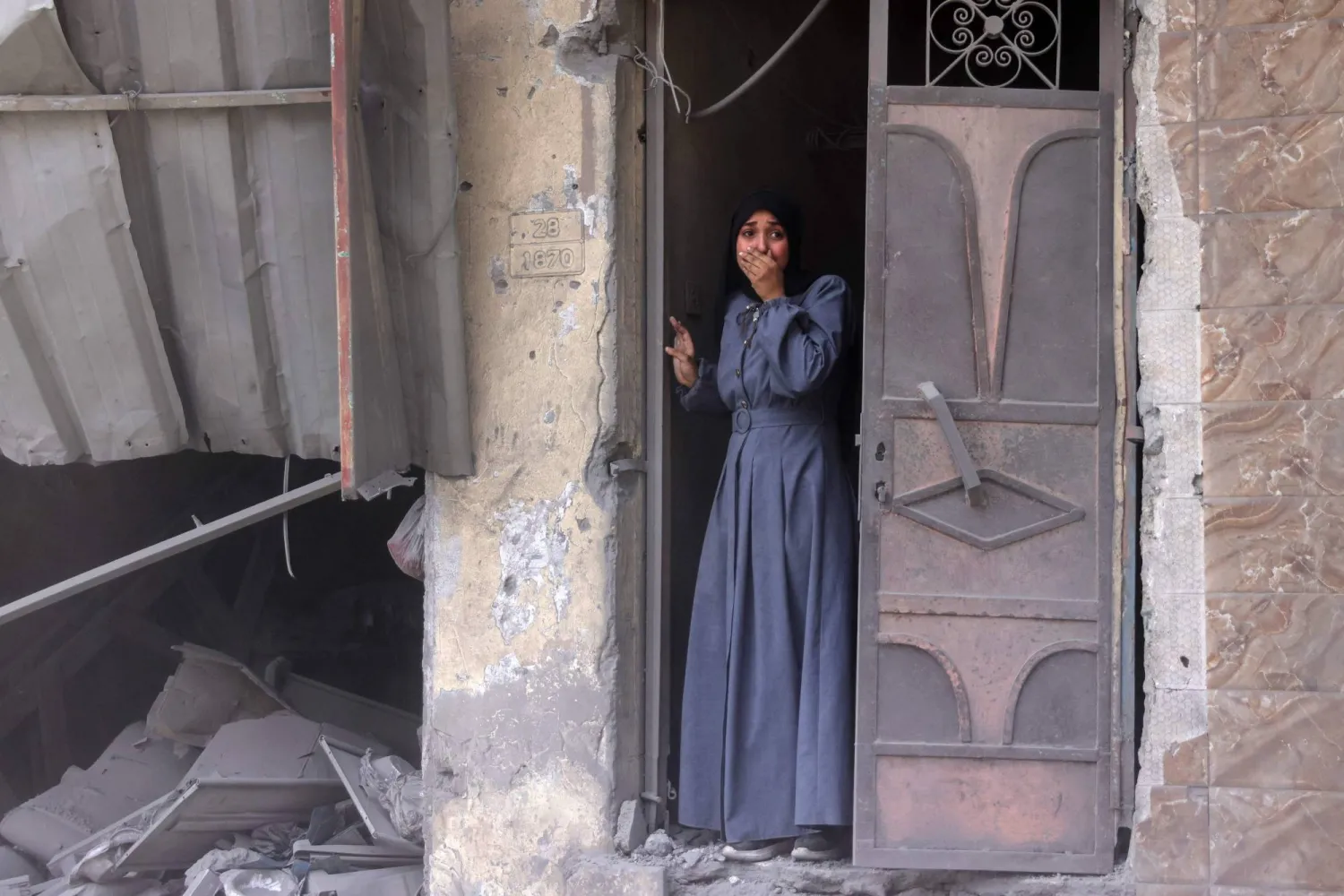 فلسطينية تقف على باب منزلها تعاين متأثرة أثار ضربة إسرائيلية في مدينة غزة أمس (أ.ف.ب)