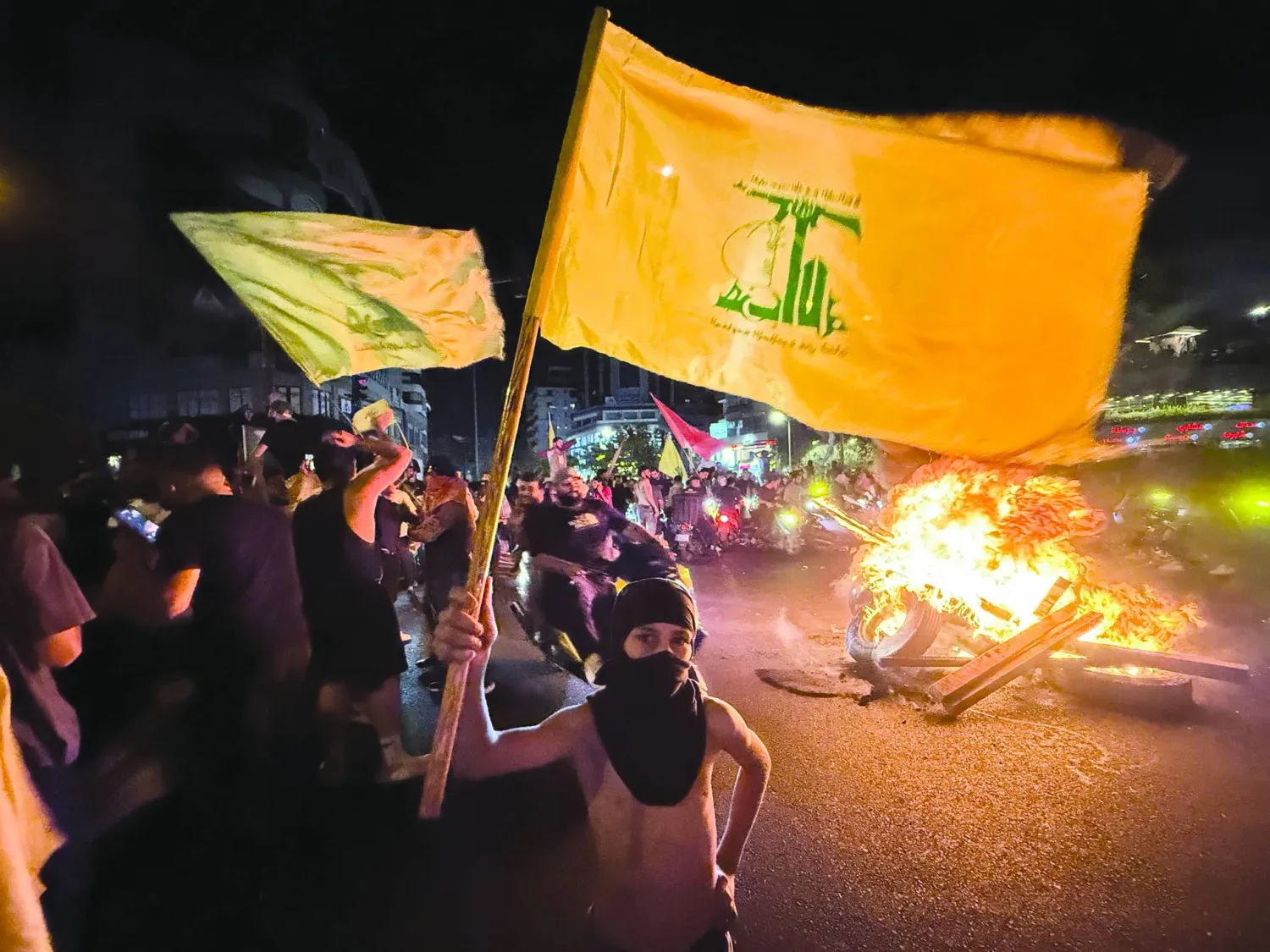 Supporters of Lebanon's Hezbollah militant group block the streets with burning tires as they rally in cars and motorbikes to protest the government's endorsement of a plan to disarm it, in Beirut's southern suburbs early on August 8, 2025.  (Photo by Ibrahim AMRO / AFP)