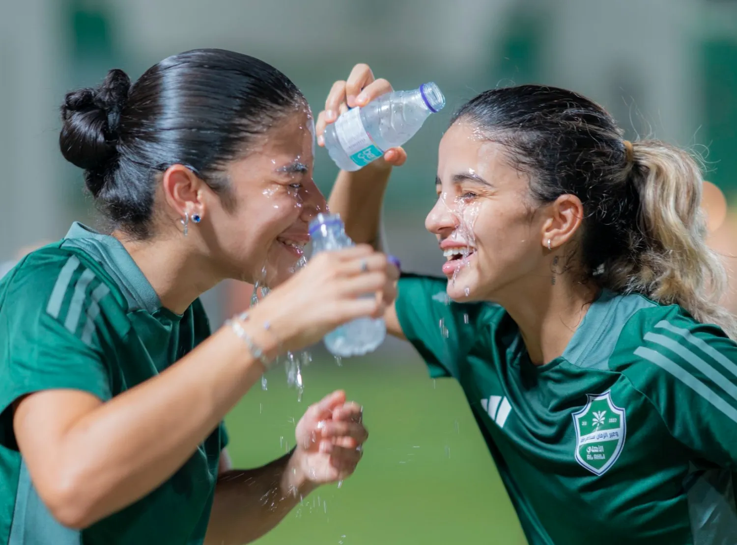 لاعبتان من الأهلي تسكبان الماء على وجهيهما بعد نهاية التدريبات (موقع النادي)
