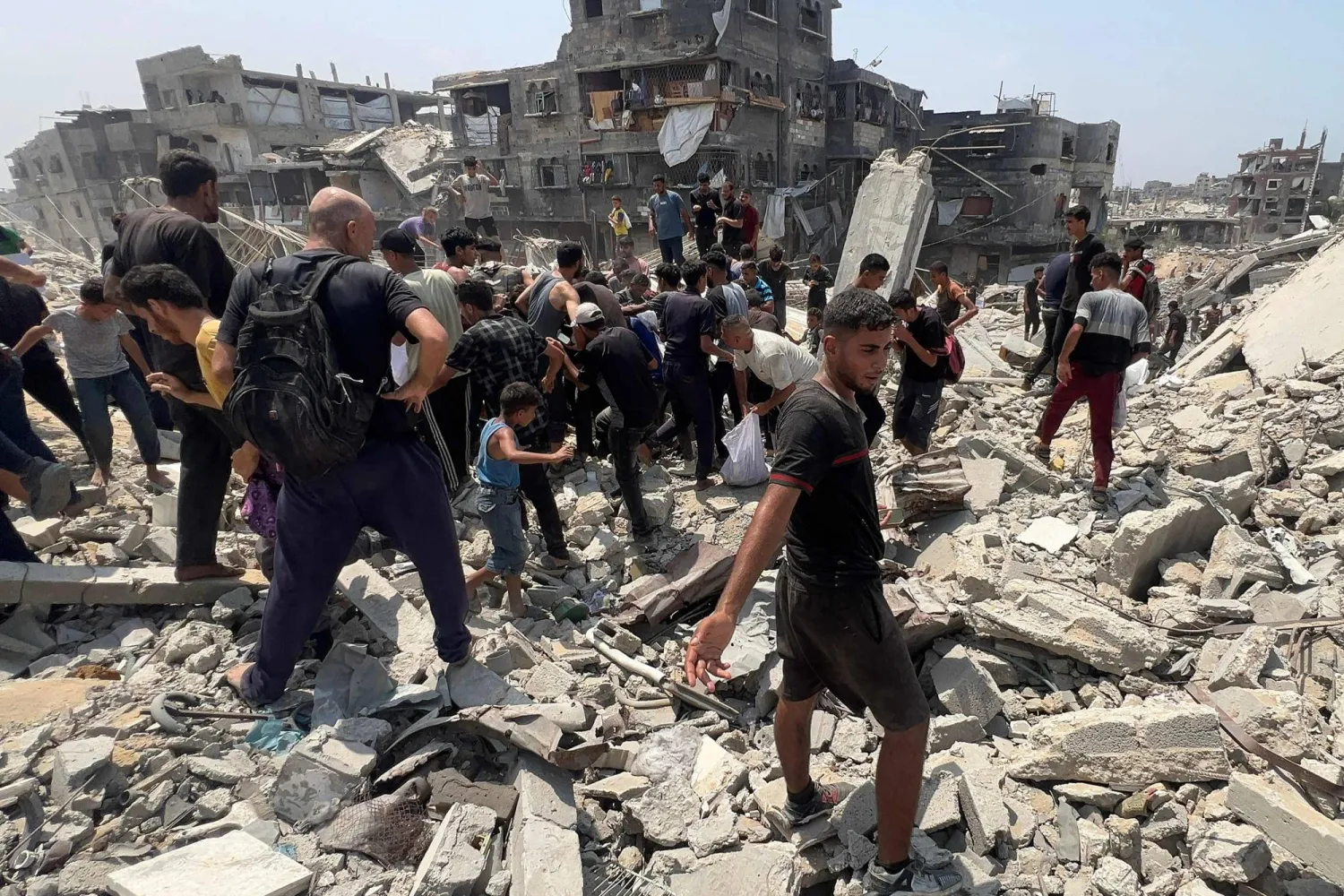 فلسطينيون يتدافعون حول طرد إنساني أسقطته طائرة عسكرية في جباليا بشمال قطاع غزة (أ.ف.ب)