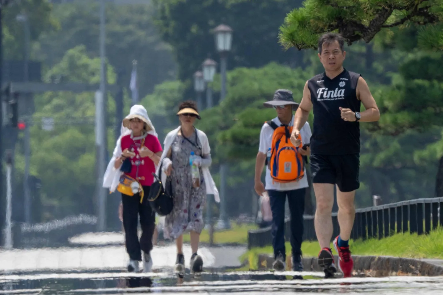 A man runs in the hot sun on a sidewalk near the Imperial Palace in Tokyo on August 6, 2025. (Photo by Kazuhiro NOGI / AFP)
