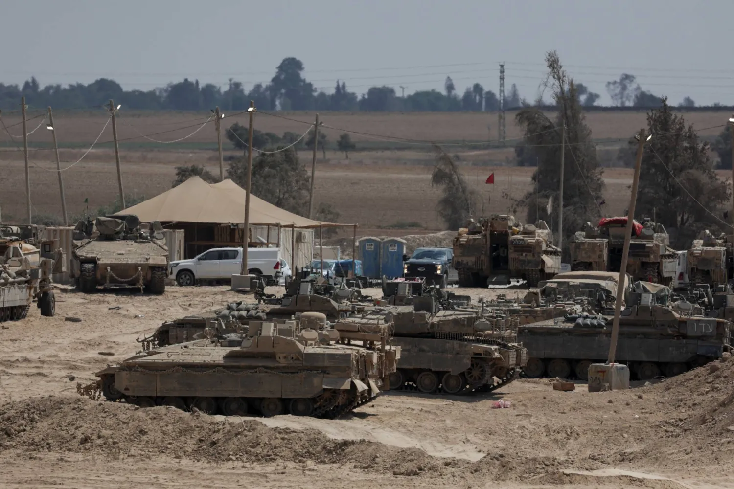 مركبات إسرائيلية تقف بجوار السياج الحدودي بين إسرائيل وغزة يوم الأحد (رويترز)