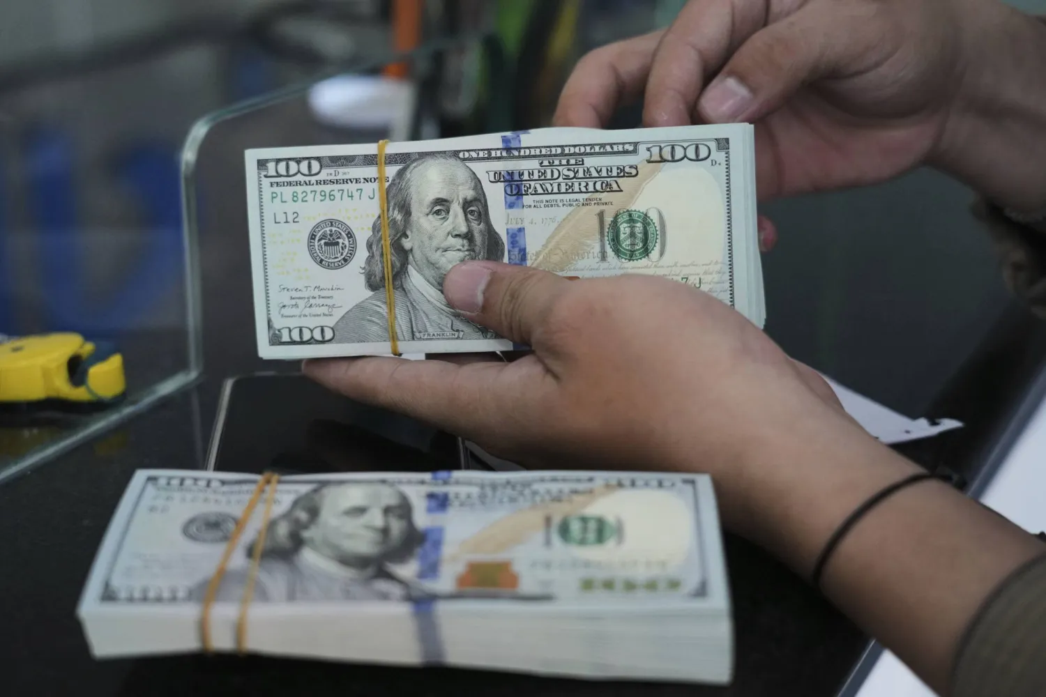 An employee counts US dollar notes at a money changer in Jakarta, Indonesia, Thursday, Aug. 7, 2025. (AP Photo/Tatan Syuflana)