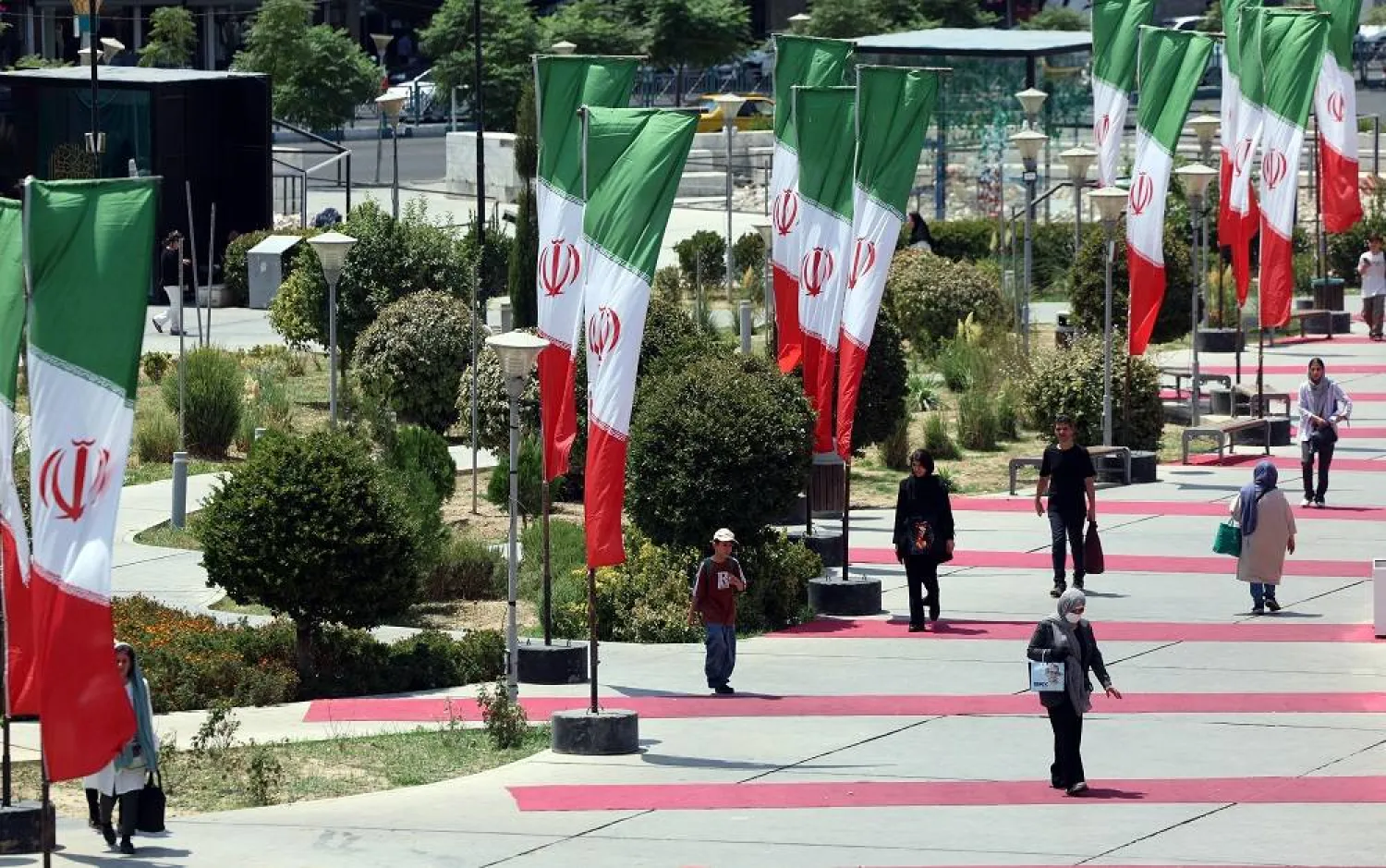 People walk next to Iranian national flags in a street in Tehran, Iran, 10 August 2025. (EPA)