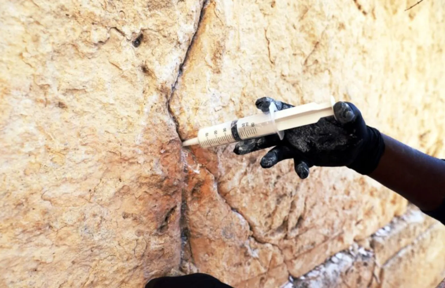 Laborer injects a type of grout into the gaps and fissures in the stones of the Western Wall, Judaism's holiest prayer site, as part of the Israel Antiquities Authority treatment of the ancient stones, in Jerusalem's Old City February 23, 2021. REUTERS/Ronen Zvulun 