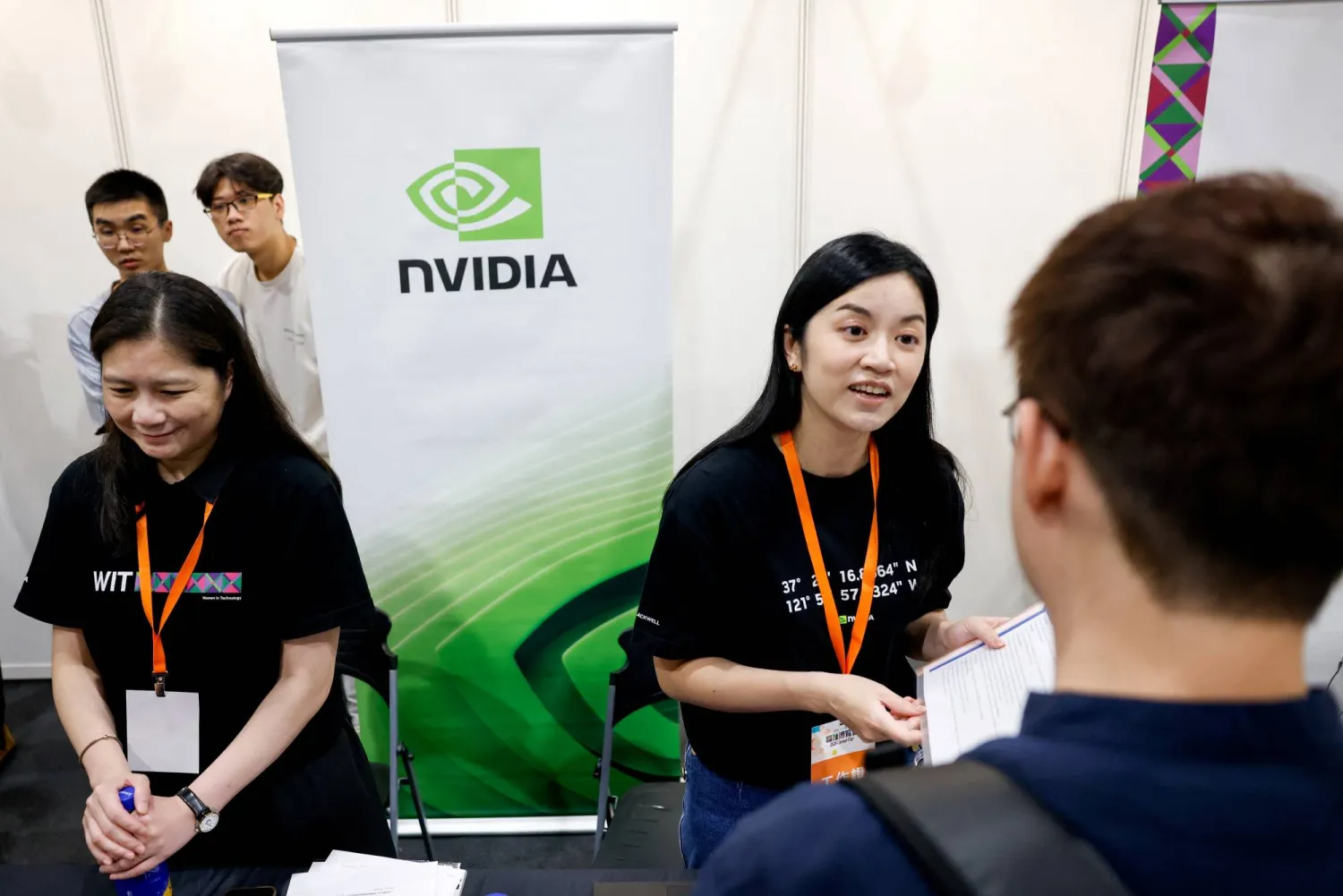 أناس يستفسرون عن الوظائف الشاغرة داخل جناح «إنفيديا» بقسم أشباه الموصلات بمعرض التوظيف في تايبيه (رويترز)