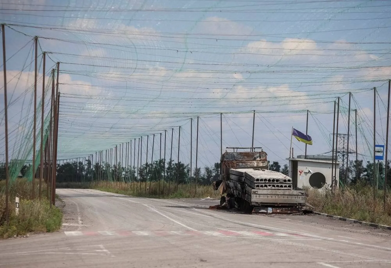 A view shows a burned vehicle and anti-drone nets installed over a road near the frontline town of Dobropillia, amid Russia's attack on Ukraine, in Donetsk region, Ukraine August 10, 2025. (Reuters)