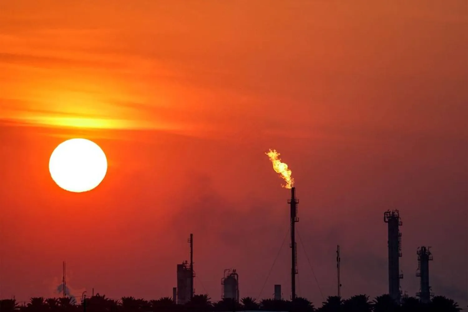The sun sets behind burning gas flares at the Dora (Daura) Oil Refinery Complex in Baghdad on December 22, 2024. (AFP)