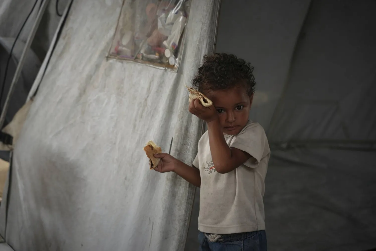 طفل فلسطيني يمسح العرق عن جبينه جراء الحرارة في خيمة عائلته بمدينة غزة الثلاثاء (أ.ب)