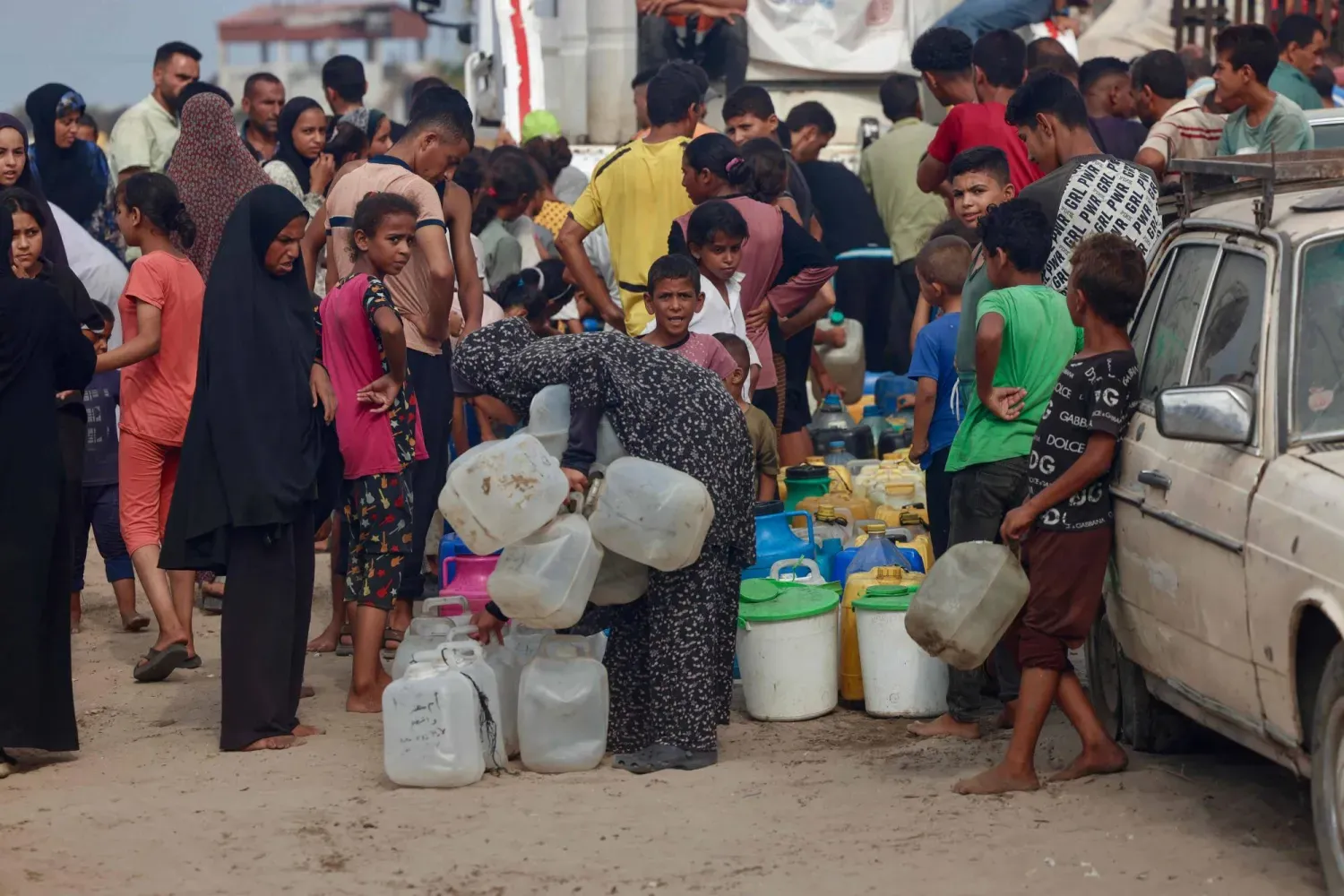 Filistinliler, dün Gazze Şeridi'nin güneyindeki Han Yunus'ta kavurucu sıcakta içme suyu almak için sıraya girdi (AFP)