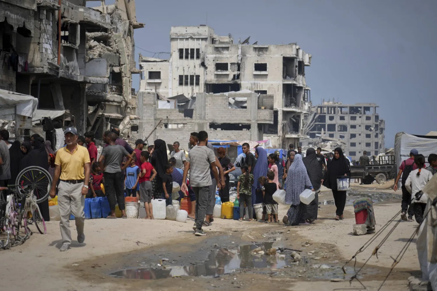 In the summer heat, Palestinians line up to collect water from a distribution point in Gaza City, Tuesday, Aug. 12, 2025. (AP Photo/Jehad Alshrafi)