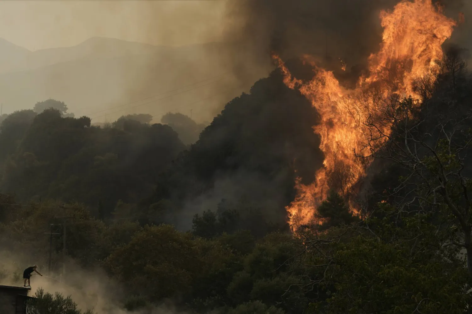 A man fights against a wildfire in Vounteni village, on the outskirts of Patras, western Greece, Wednesday, Aug. 13, 2025. (AP Photo/Thanassis Stavrakis)