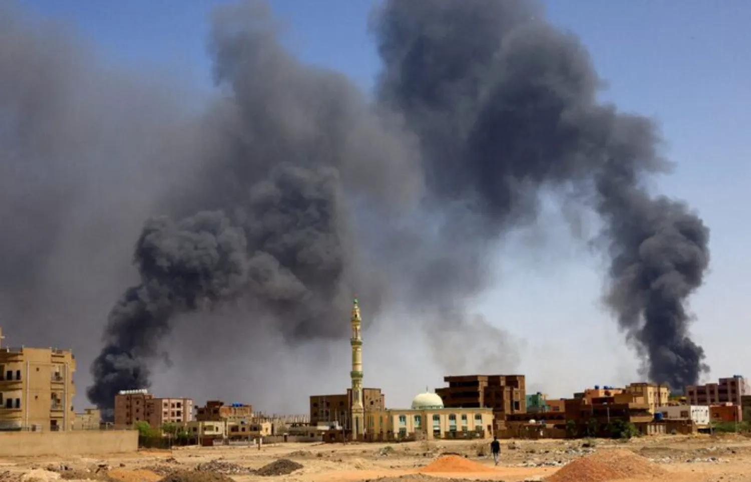 A man walks while smoke rises above buildings after aerial bombardment, during clashes between the paramilitary Rapid Support Forces and the army in Khartoum North, Sudan, May 1, 2023. REUTERS/Mohamed Nureldin Abdallah/File Photo 