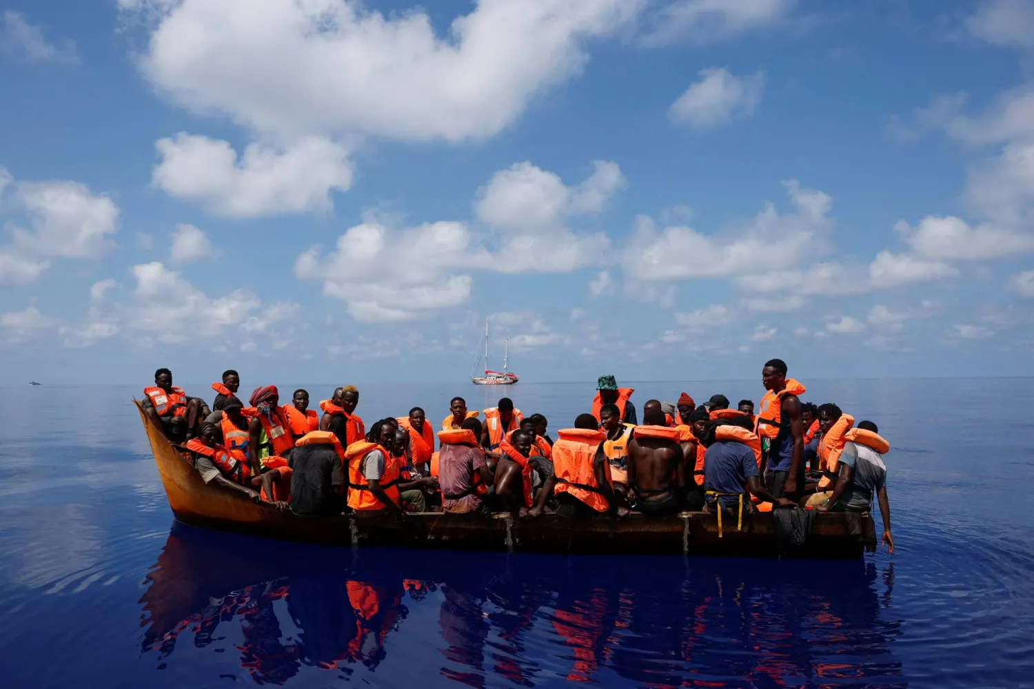 مهاجرون على متن قارب بالقرب من قارب إنقاذ في المياه الدولية جنوب لامبيدوزا في وسط البحر المتوسط... 11 أغسطس 2024 (رويترز)