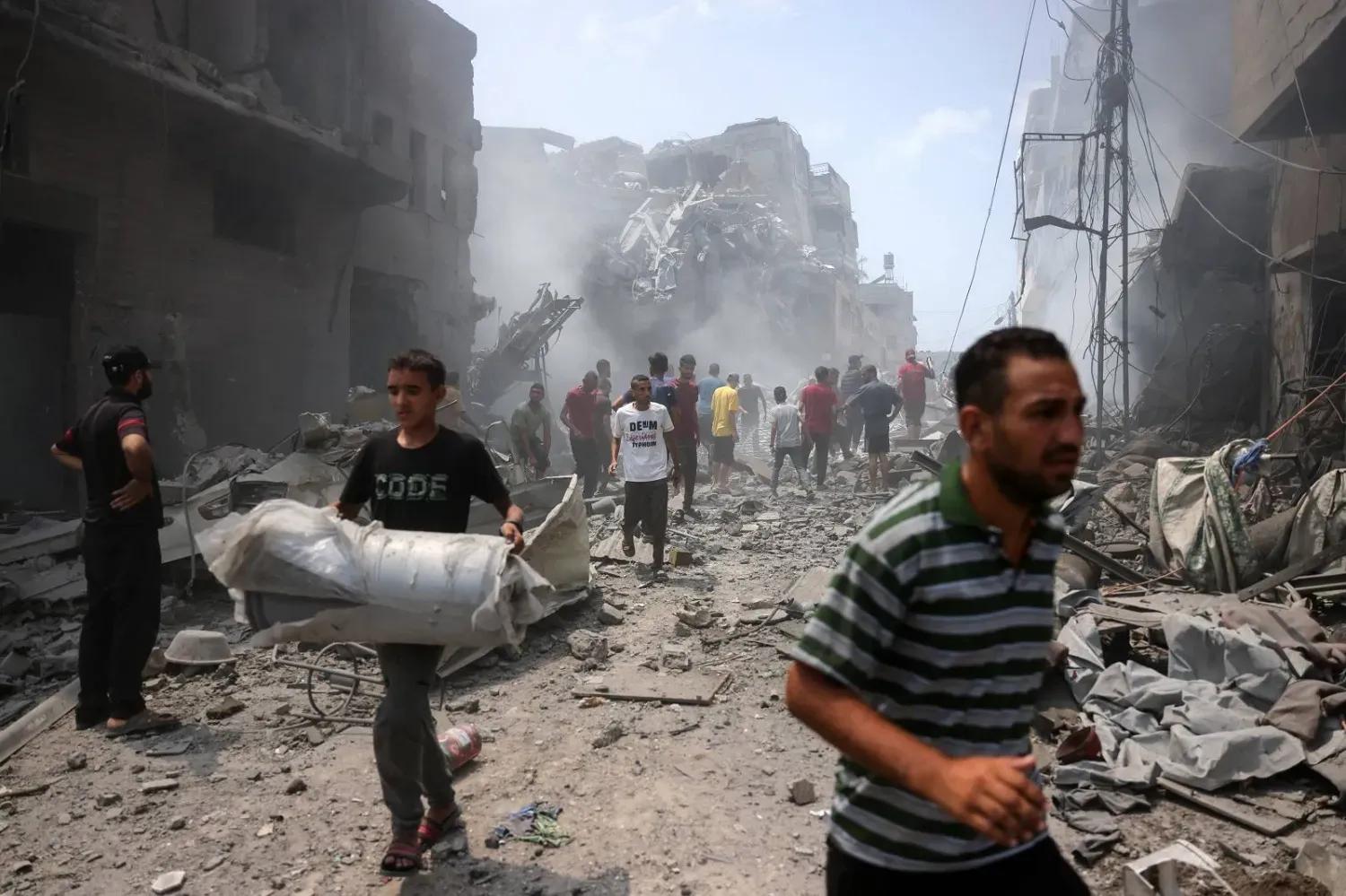 Gazze'nin güneyindeki ez-Zeytun mahallesini hedef alan İsrail hava saldırısının yol açtığı yıkımı inceleyen Filistinliler (AFP)