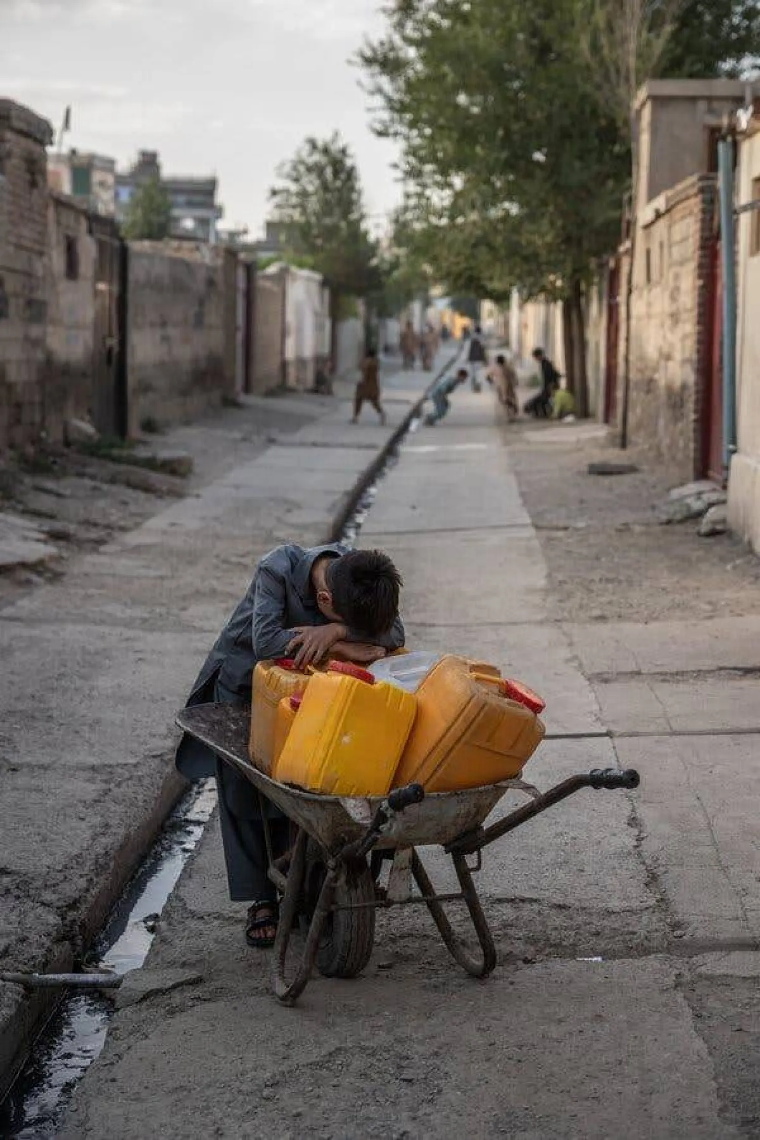 صبي يستريح في طريقه إلى جلب الماء من خارج منزله في كابل بأفغانستان الشهر الماضي (نيويورك تايمز)