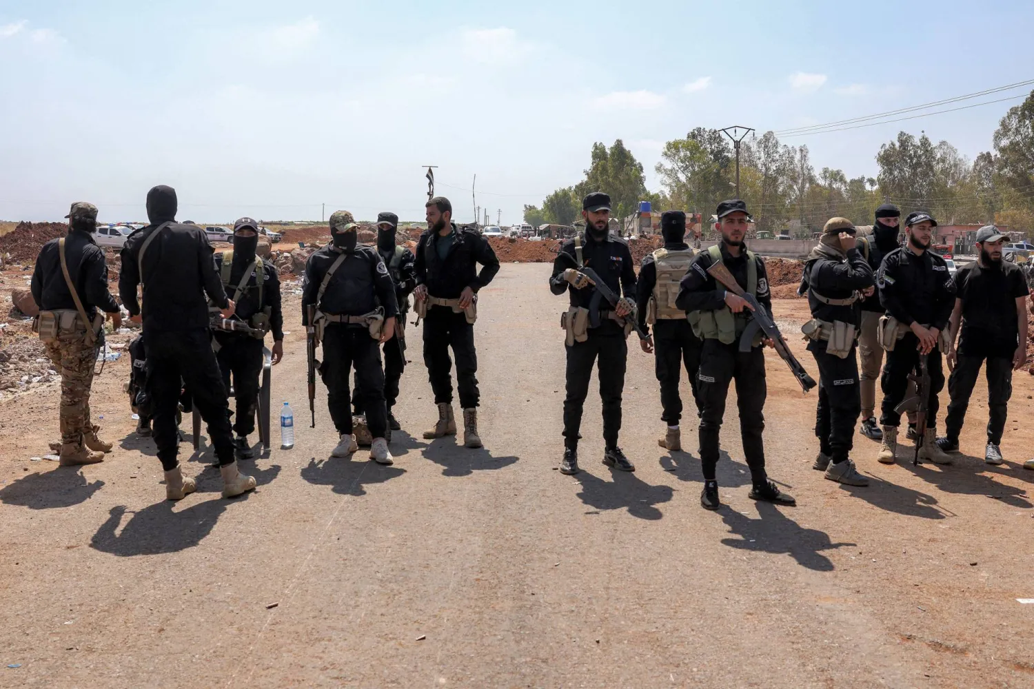 Syrian government security forces stand near an earth barrier that they created as a buffer during their deployment in Busra al-Harir in Syria's southern Daraa province on July 21, 2025.  (Photo by Bakr ALkasem / AFP)