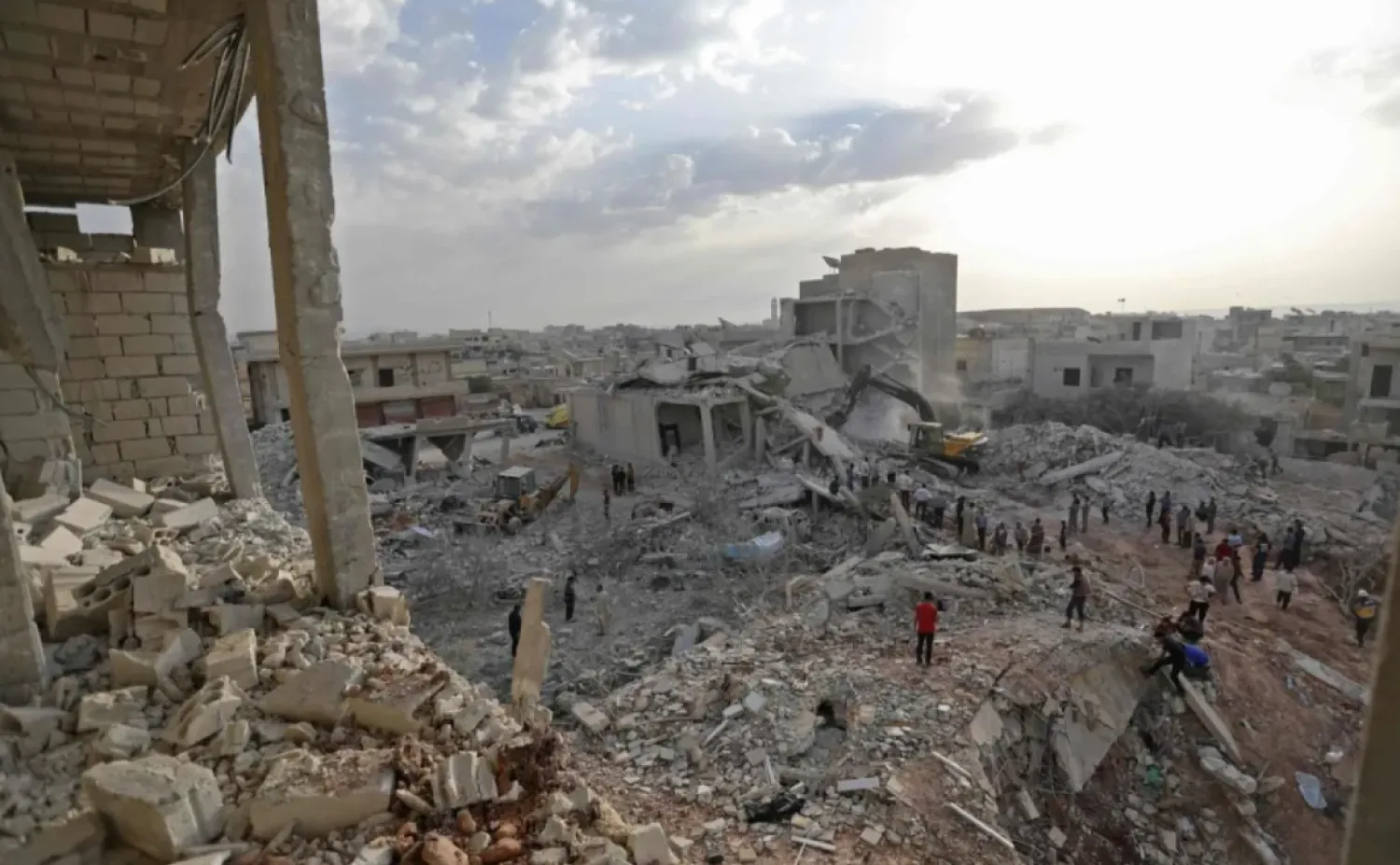 Syrians gather amidst destruction in Zardana, in the mostly rebel-held northern Syrian Idlib province, after airstrikes in the area late on June 8, 2018 | AFP
