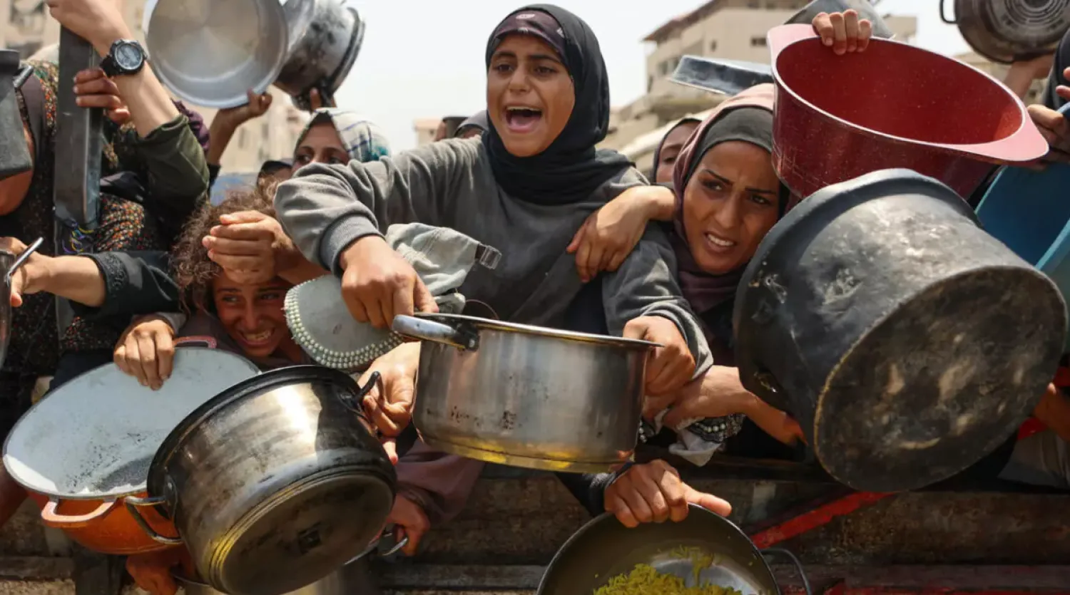 Palestinians gather to receive cooked meals from a food distribution center in Gaza City on August 13, 2025. © Omar al-Qattaa, AFP
